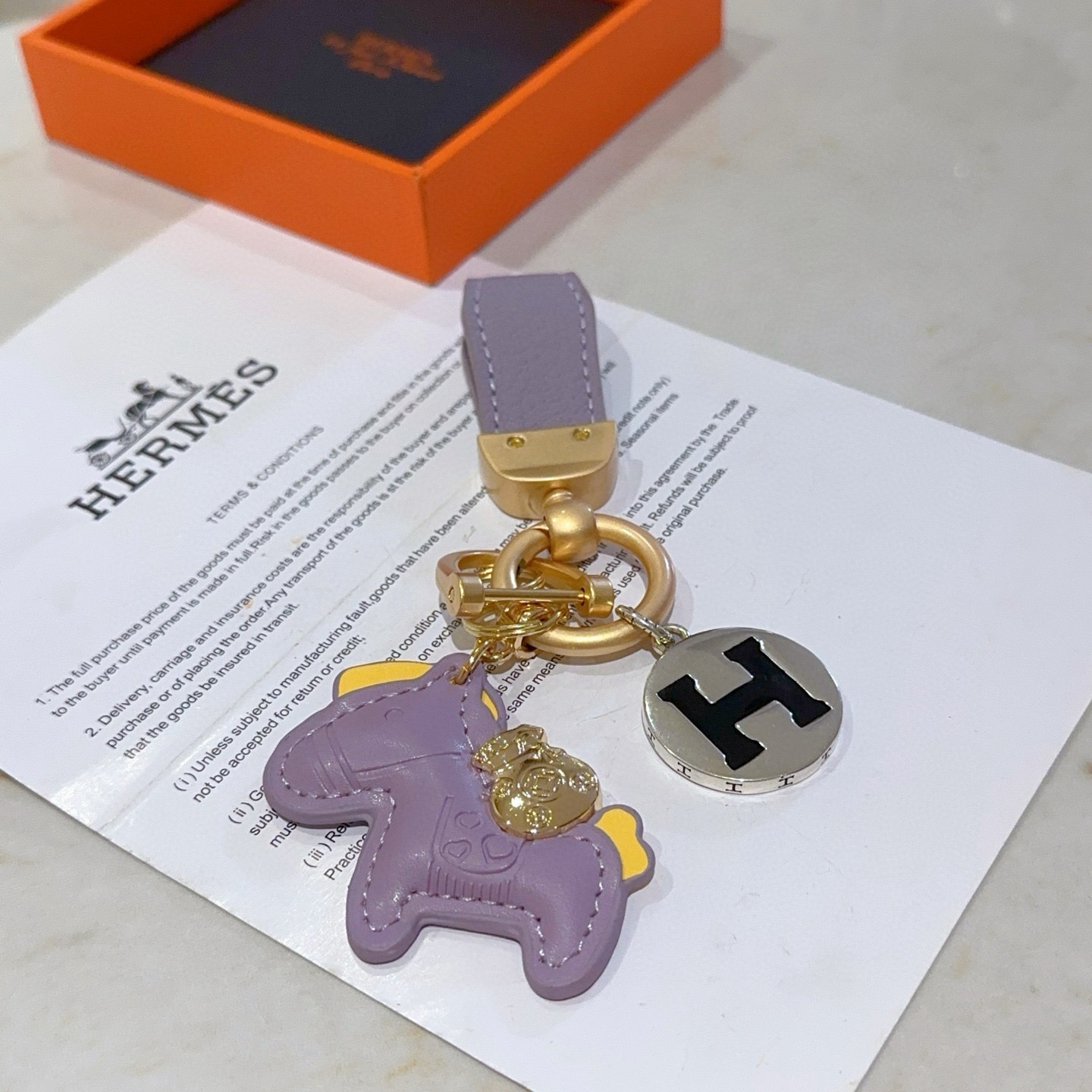 Ciondolo chiave Hermes Rodeo Horse H Logo ciondolo in metallo color oro opaco pelle lavanda accento in pelle gialla metallo argentato con logo H smaltato nero lunghezza totale 10 cm