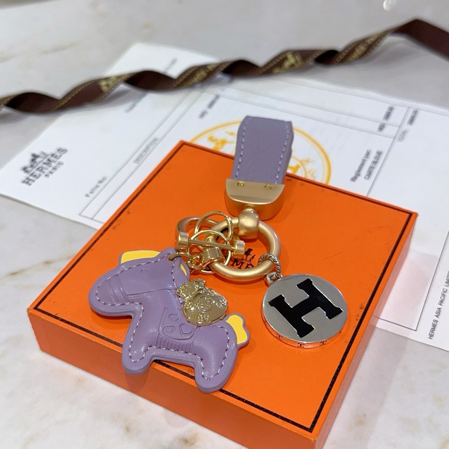 Ciondolo chiave Hermes Rodeo Horse H Logo ciondolo in metallo color oro opaco pelle lavanda accento in pelle gialla metallo argentato con logo H smaltato nero lunghezza totale 10 cm
