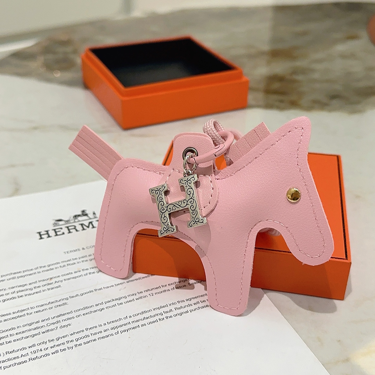 Pendentif Hermes Rodeo Horse Charm Sakura en cuir rose avec breloque H gravée argentée, clou en forme d'œil doré 12 cm