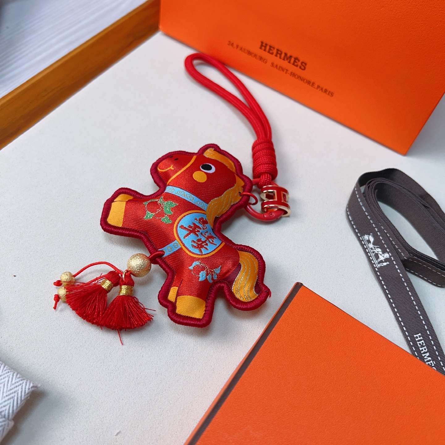 Ciondolo Hermes Anno del cavallo Lucky Nappa Tessuto rosso con dettagli decorativi oro blu verde cinturino in cordino rosso hardware in metallo color oro nappe rosse lunghezza totale 12 cm