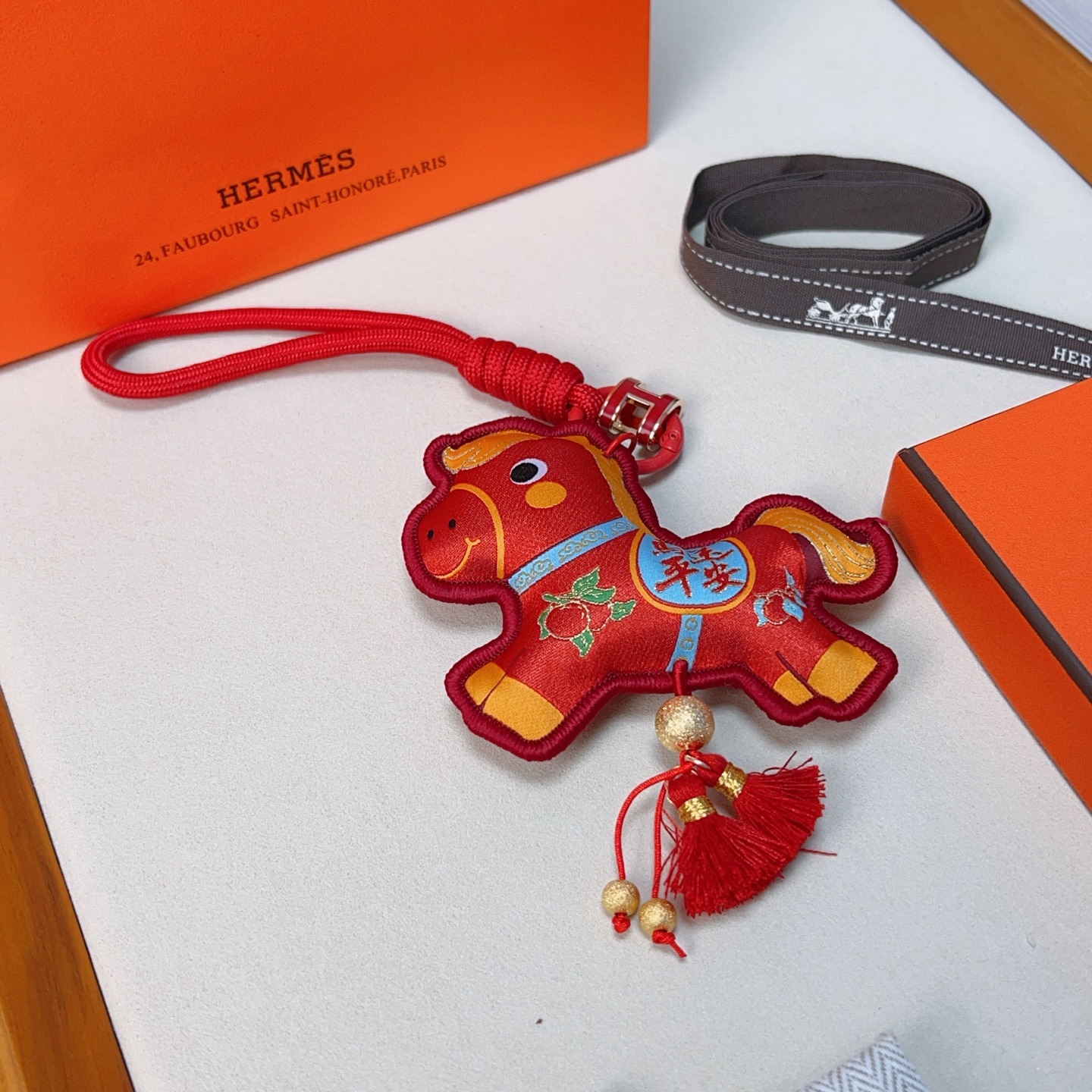 Ciondolo Hermes Anno del cavallo Lucky Nappa Tessuto rosso con dettagli decorativi oro blu verde cinturino in cordino rosso hardware in metallo color oro nappe rosse lunghezza totale 12 cm