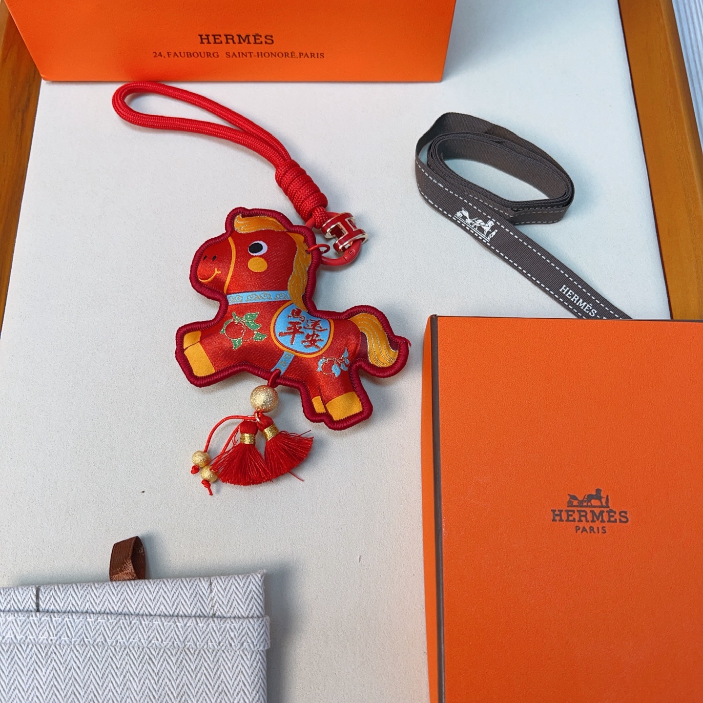 Ciondolo Hermes Anno del cavallo Lucky Nappa Tessuto rosso con dettagli decorativi oro blu verde cinturino in cordino rosso hardware in metallo color oro nappe rosse lunghezza totale 12 cm