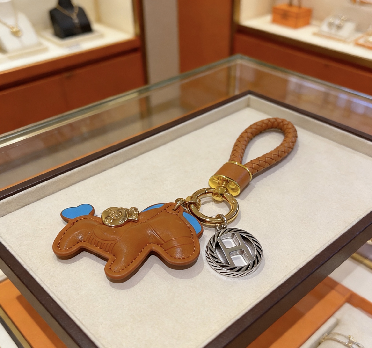 Ciondolo con chiave Hermes Rodeo con cinturino intrecciato Pelle marrone oro con accenti celesti Hardware in metallo color oro e argento Lunghezza totale 12 cm