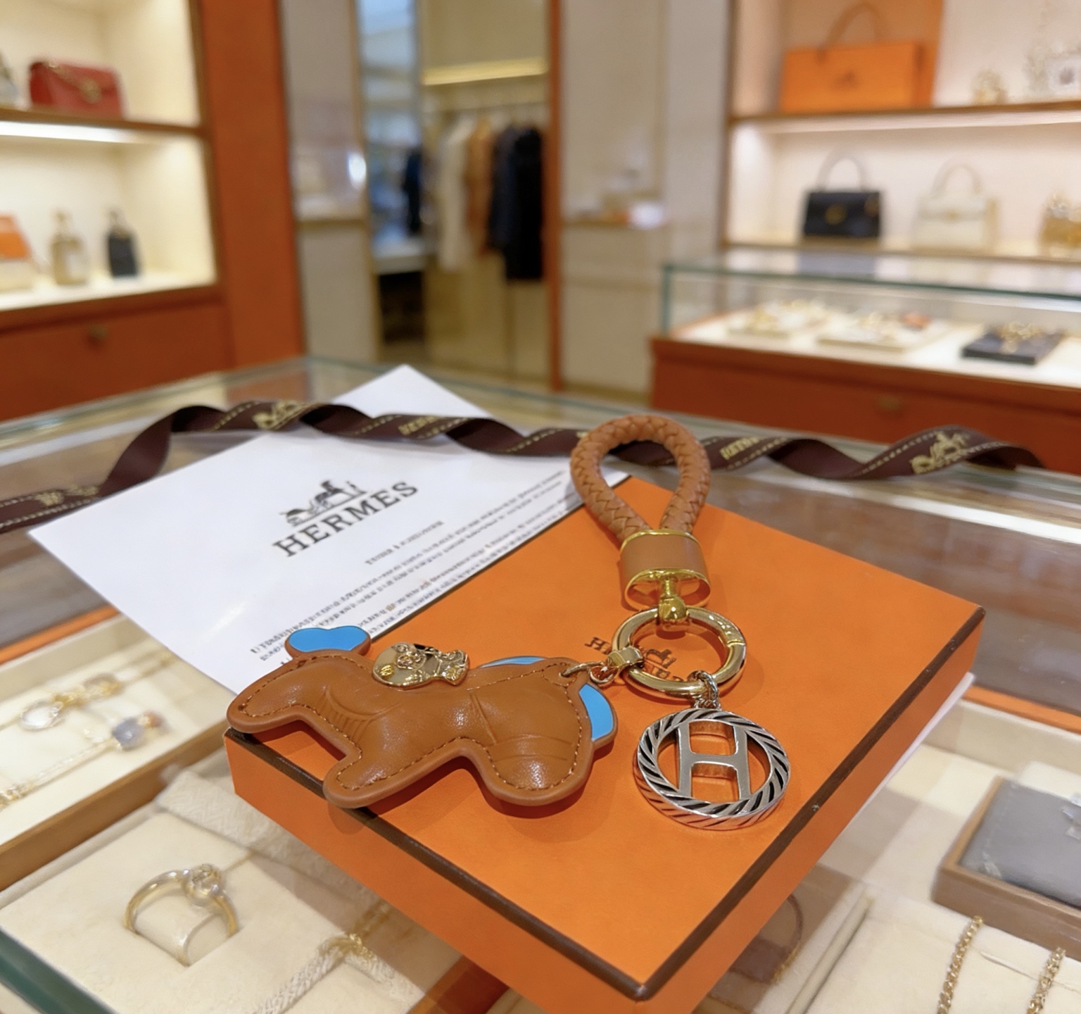 Ciondolo con chiave Hermes Rodeo con cinturino intrecciato Pelle marrone oro con accenti celesti Hardware in metallo color oro e argento Lunghezza totale 12 cm