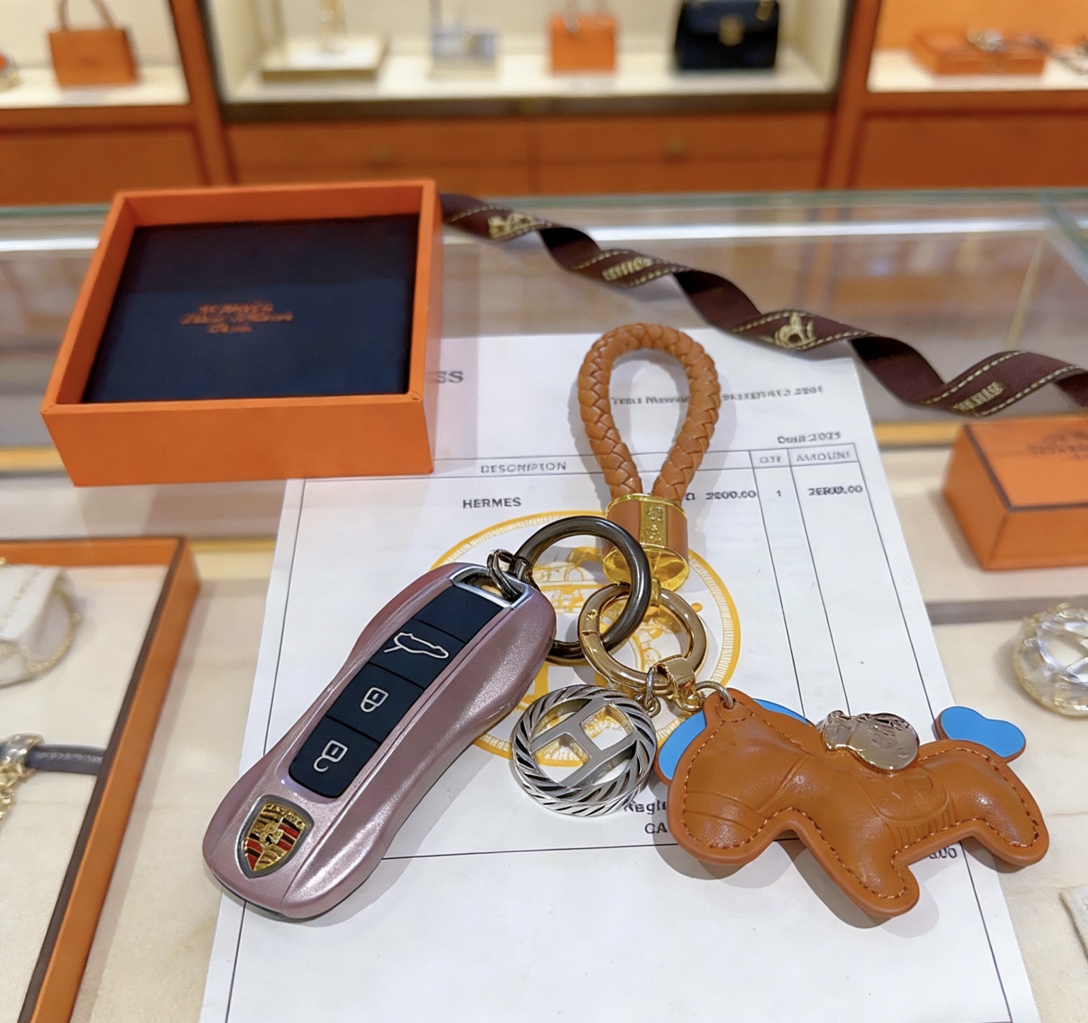Ciondolo con chiave Hermes Rodeo con cinturino intrecciato Pelle marrone oro con accenti celesti Hardware in metallo color oro e argento Lunghezza totale 12 cm