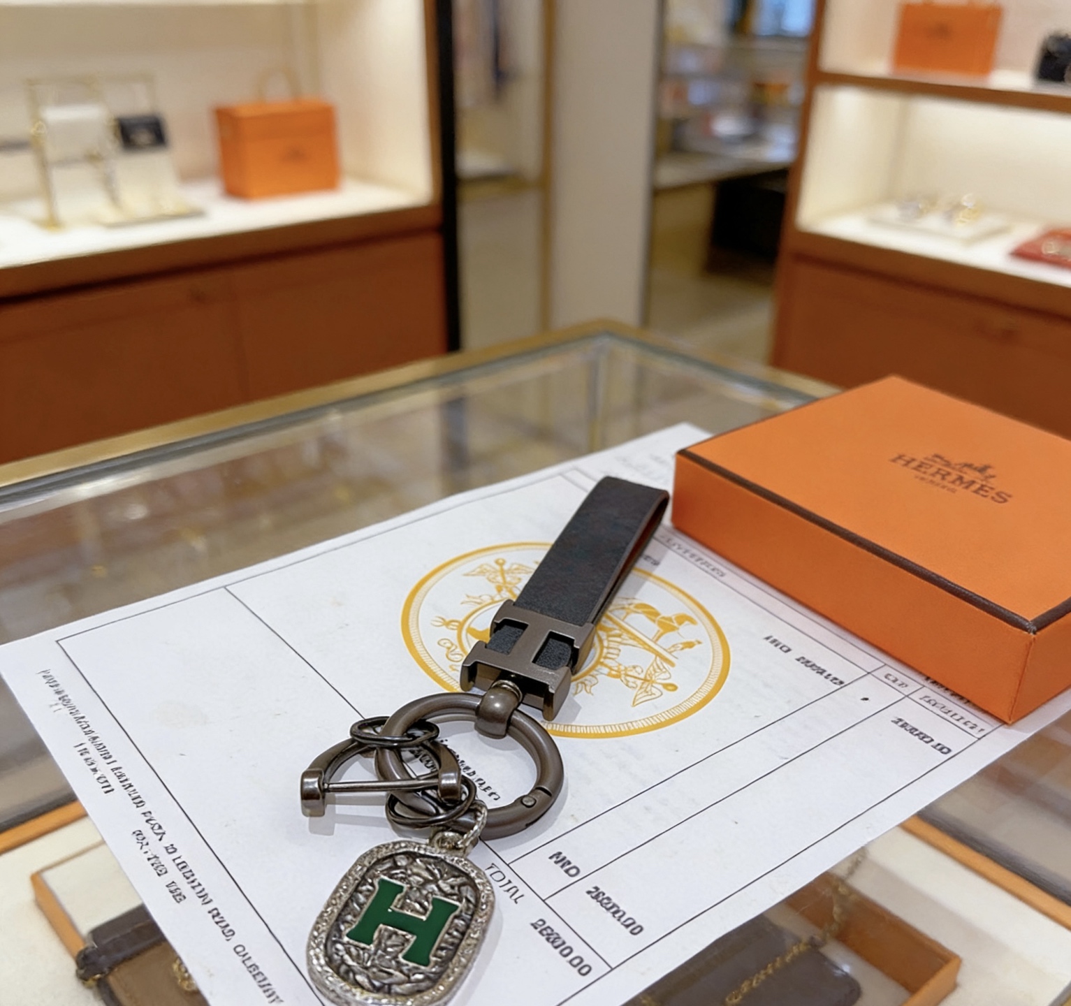 Ciondolo con chiave in pelle con logo Hermes H. Dettaglio H in metallo grigio canna di fucile, pelle nera, smalto verde. Lunghezza cinturino 10 cm