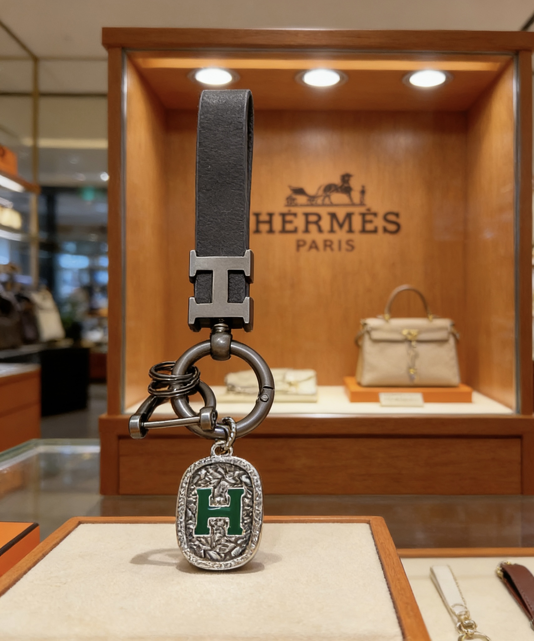 Ciondolo portachiavi con cinturino in pelle con logo Hermes H. Dettaglio H in metallo color argento canna di fucile, pelle nera, smalto verde, lunghezza totale 10 cm
