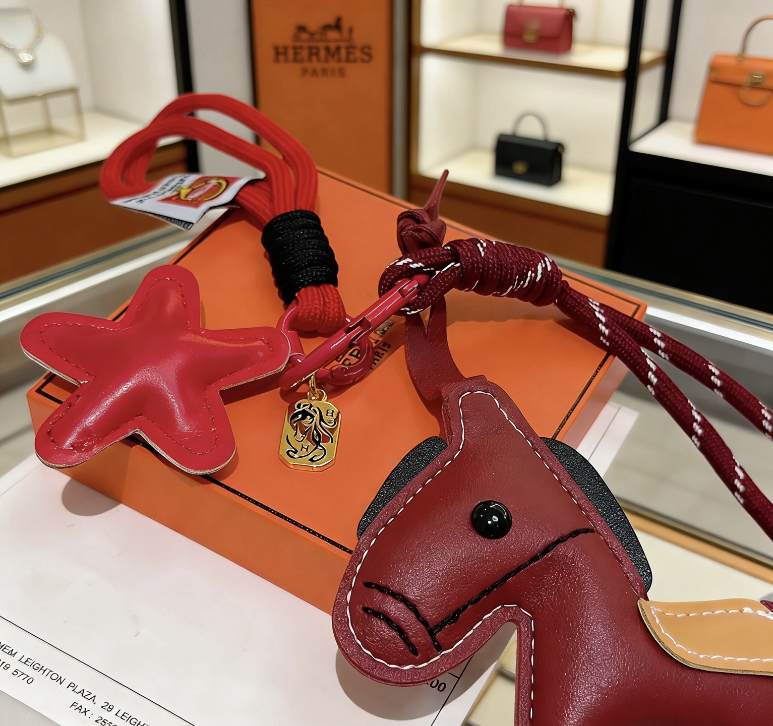 Hermes Rodeo Horse Star Bag Charm colgante Cuero rojo burdeos Silla de montar de cuero color canela Detalles en negro Herrajes de metal en tono dorado Cordón tejido rojo Longitud total de la correa de 12 cm