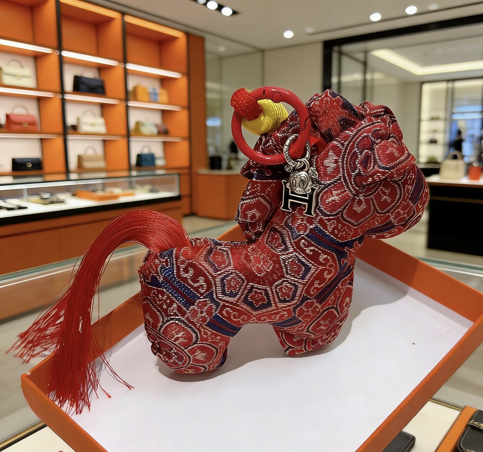 Colgante Hermes Rodeo Horse Charm Tela roja con motivos tradicionales azul marino y dorado Cordón rojo Envoltura de cordón amarillo Charm H plateado Borla roja 8 cm