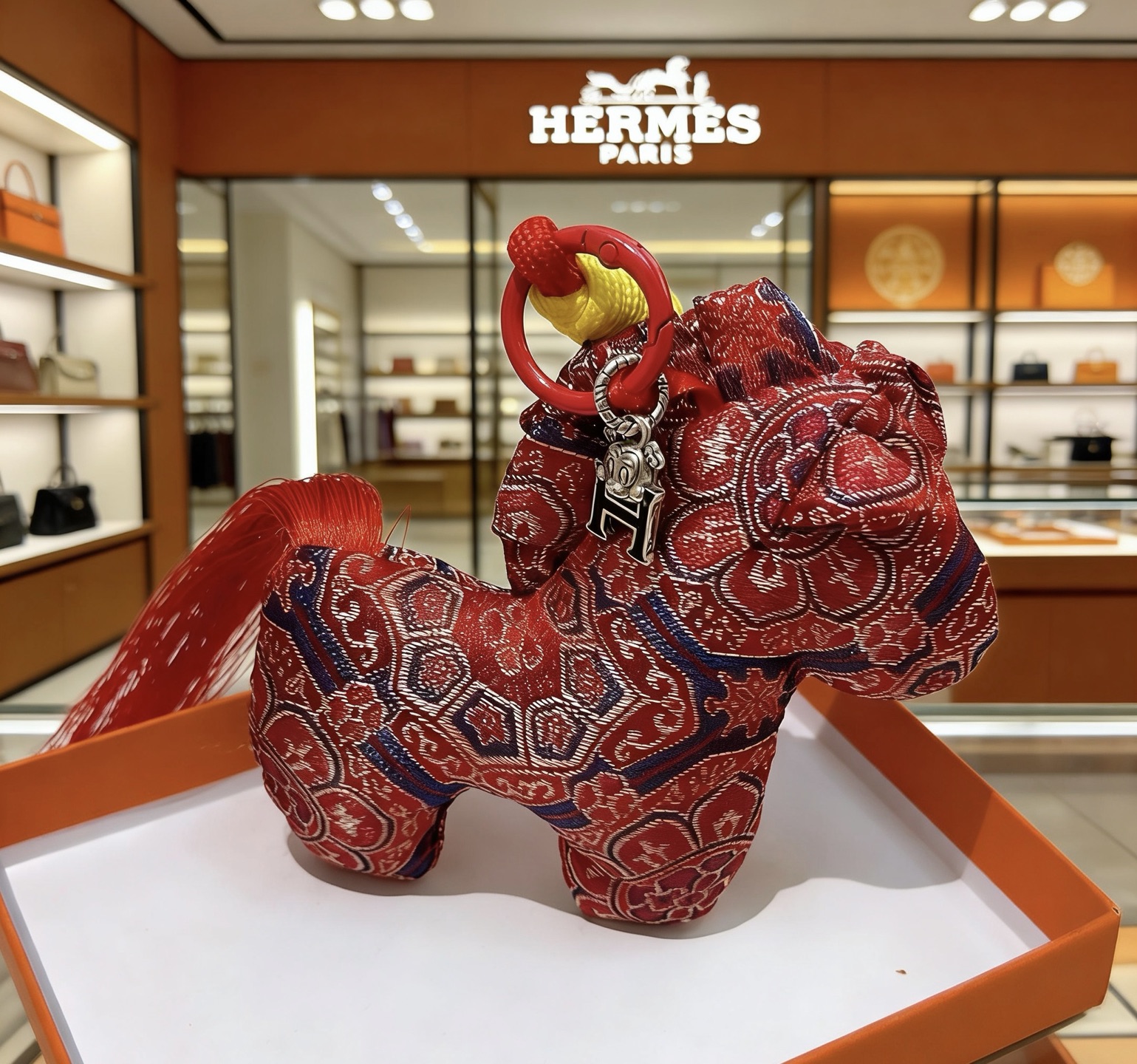 Colgante Hermes Rodeo Horse Charm Tela roja con motivos tradicionales azul marino y dorado Cordón rojo Envoltura de cordón amarillo Charm H plateado Borla roja 8 cm