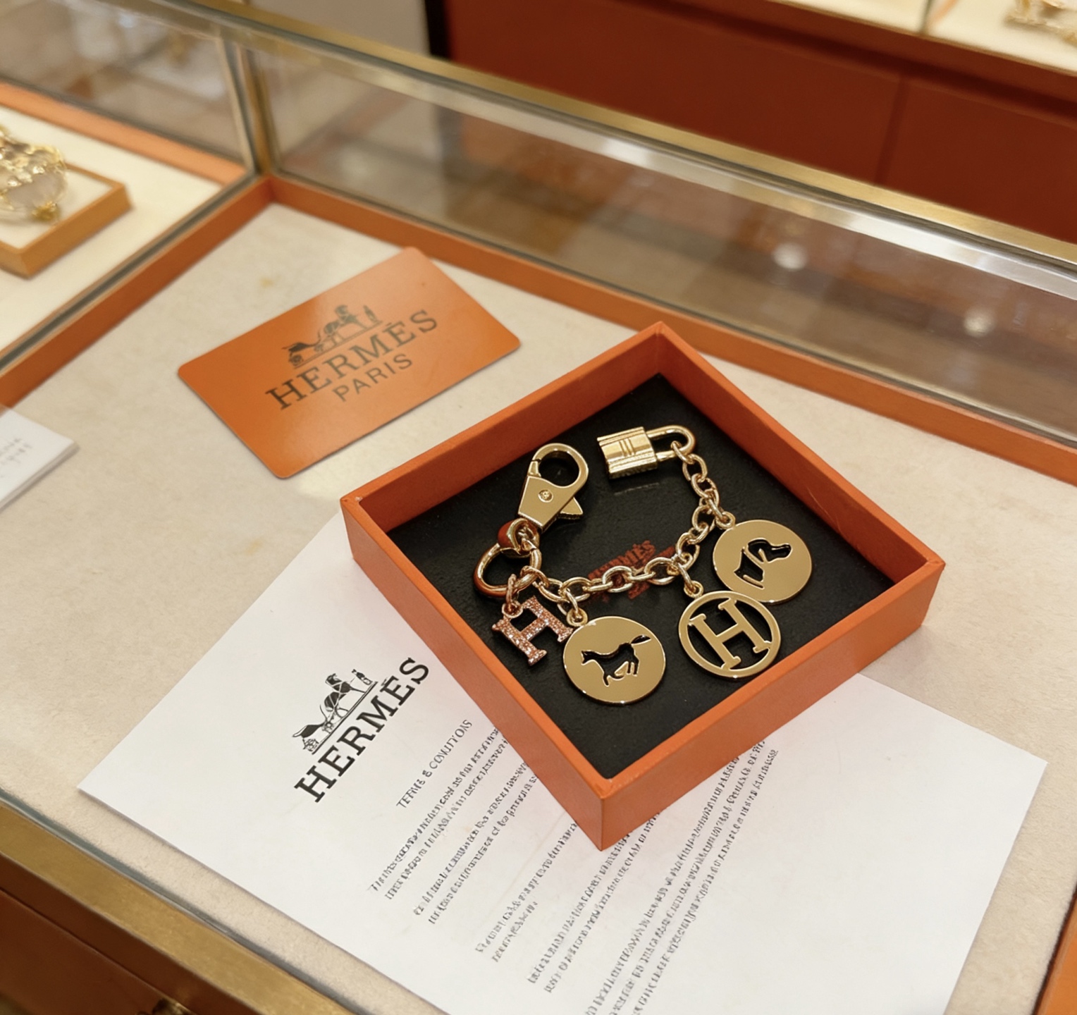 Ciondolo portachiavi con logo Hermes Equestrian H. Metallo color oro con pavé in oro rosa. Ciondolo H in smalto nero con accenti di cavallo e cane, lunghezza della catena di 12 cm.