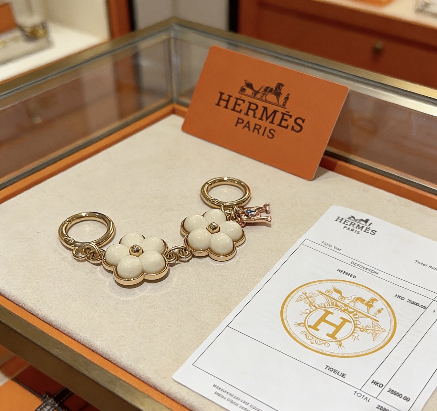 Ciondolo portachiavi Hermes Flower H Ciondolo portachiavi in ​​metallo tono oro, smalto bianco crema, ciondolo H tono oro rosa con accento blu, lunghezza totale 8 cm