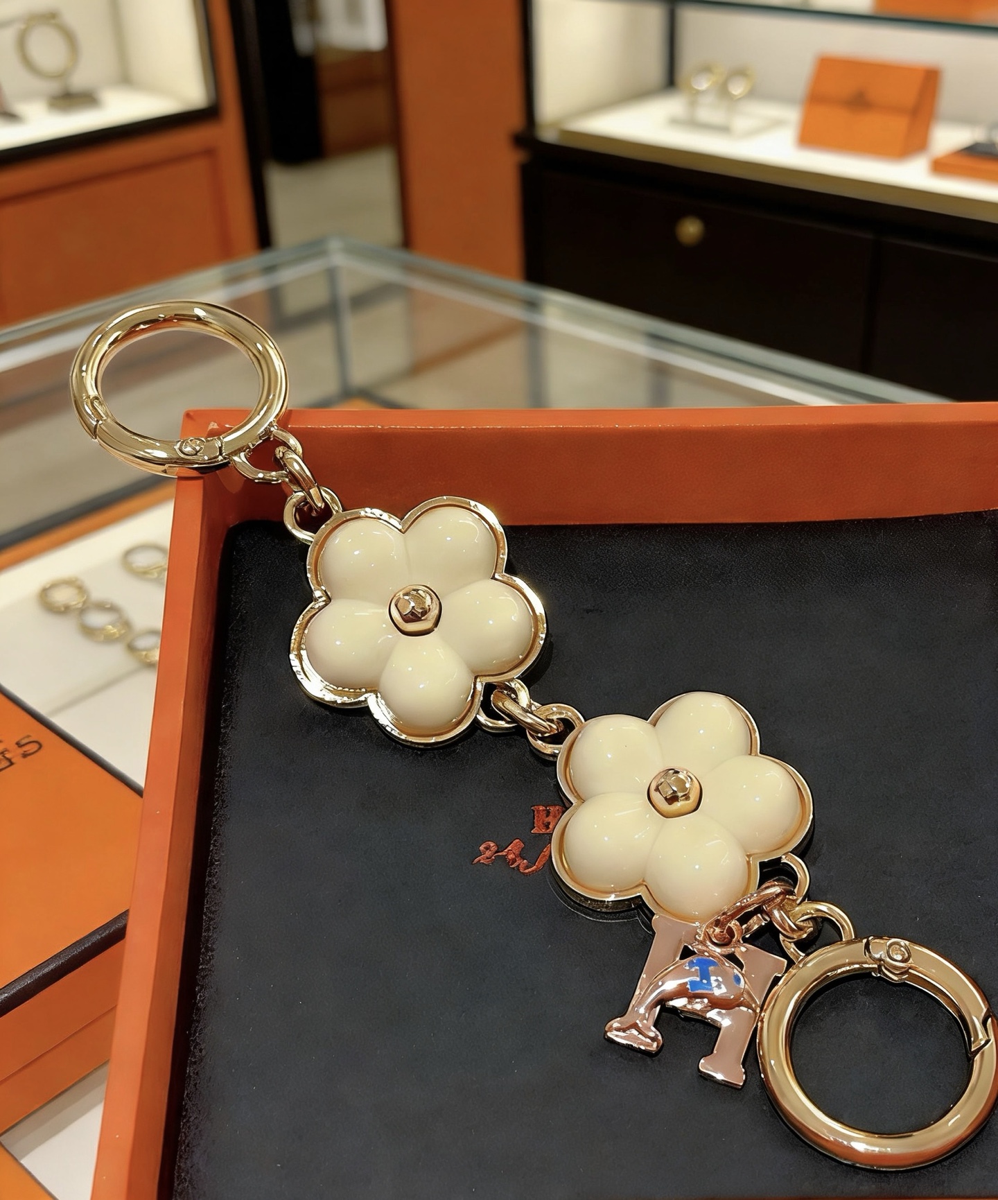 Ciondolo portachiavi Hermes Flower H Ciondolo portachiavi in ​​metallo tono oro, smalto bianco crema, ciondolo H tono oro rosa con accento blu, lunghezza totale 8 cm
