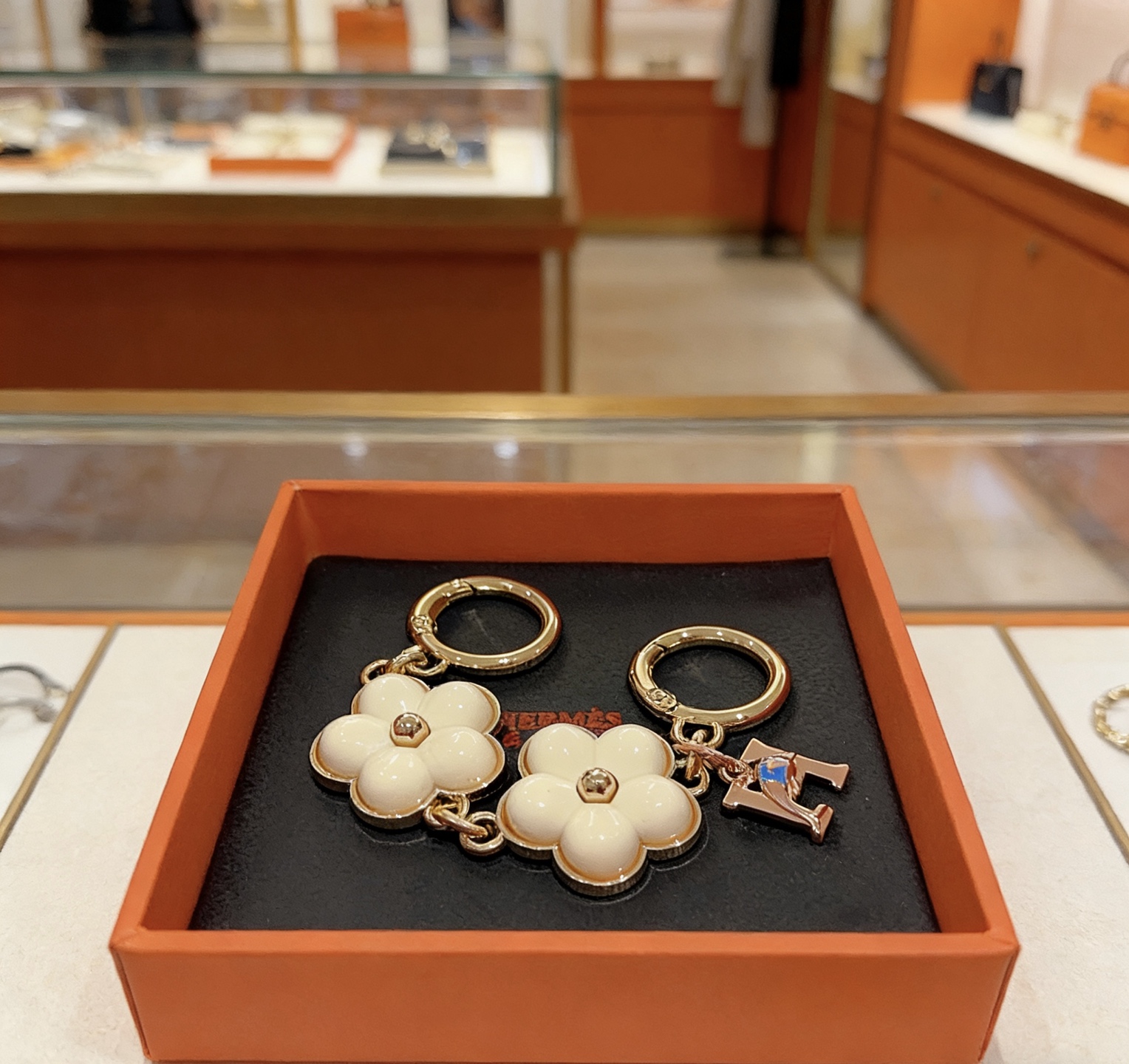 Ciondolo portachiavi Hermes Flower H Ciondolo portachiavi in ​​metallo tono oro, smalto bianco crema, ciondolo H tono oro rosa con accento blu, lunghezza totale 8 cm