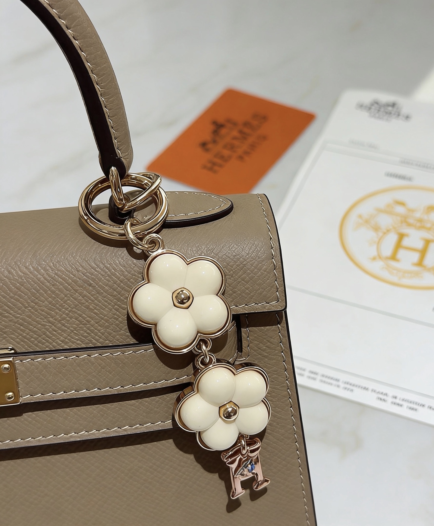 Ciondolo portachiavi Hermes Flower H Ciondolo portachiavi in ​​metallo tono oro, smalto bianco crema, ciondolo H tono oro rosa con accento blu, lunghezza totale 8 cm