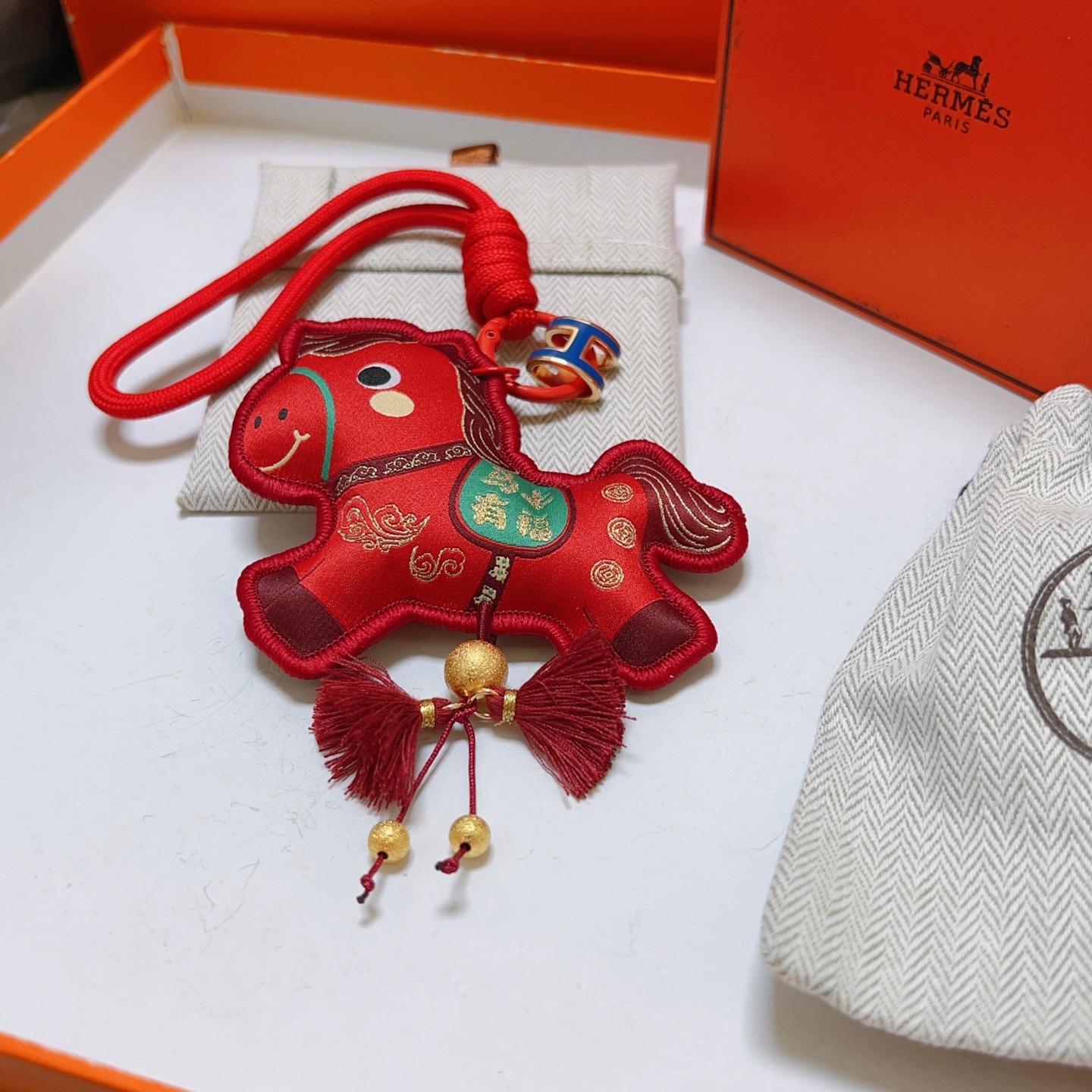 Ciondolo Hermes Chinese New Year Horse Charm Tessuto rosso con accenti dorati smalto blu H hardware verde dettaglio sella nappe bordeaux lunghezza cinturino 12 cm
