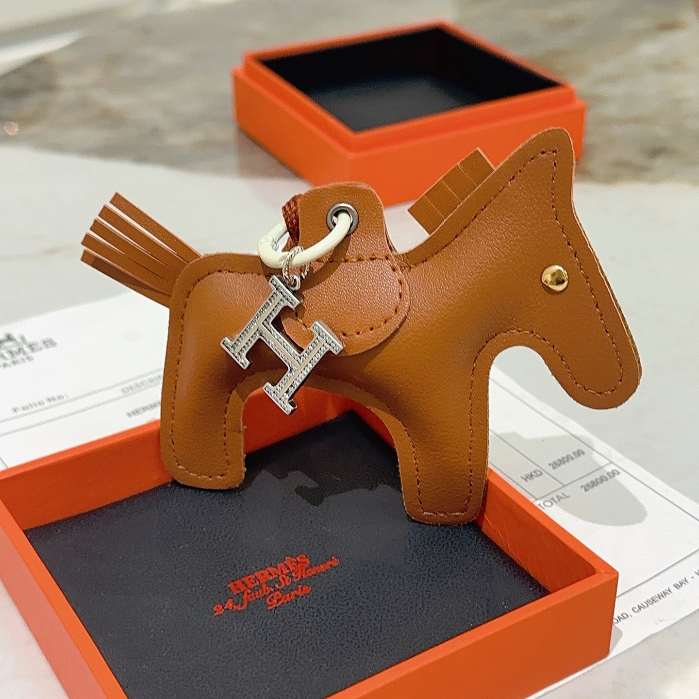 Ciondolo per borsa Hermes Rodeo Pegase Horse con pendente in cristallo H. Pelle marrone oro, metallo color argento con pavé di cristalli trasparenti, hardware bianco sporco, cordone marrone terracotta, lunghezza totale del ciondolo: 8 cm.