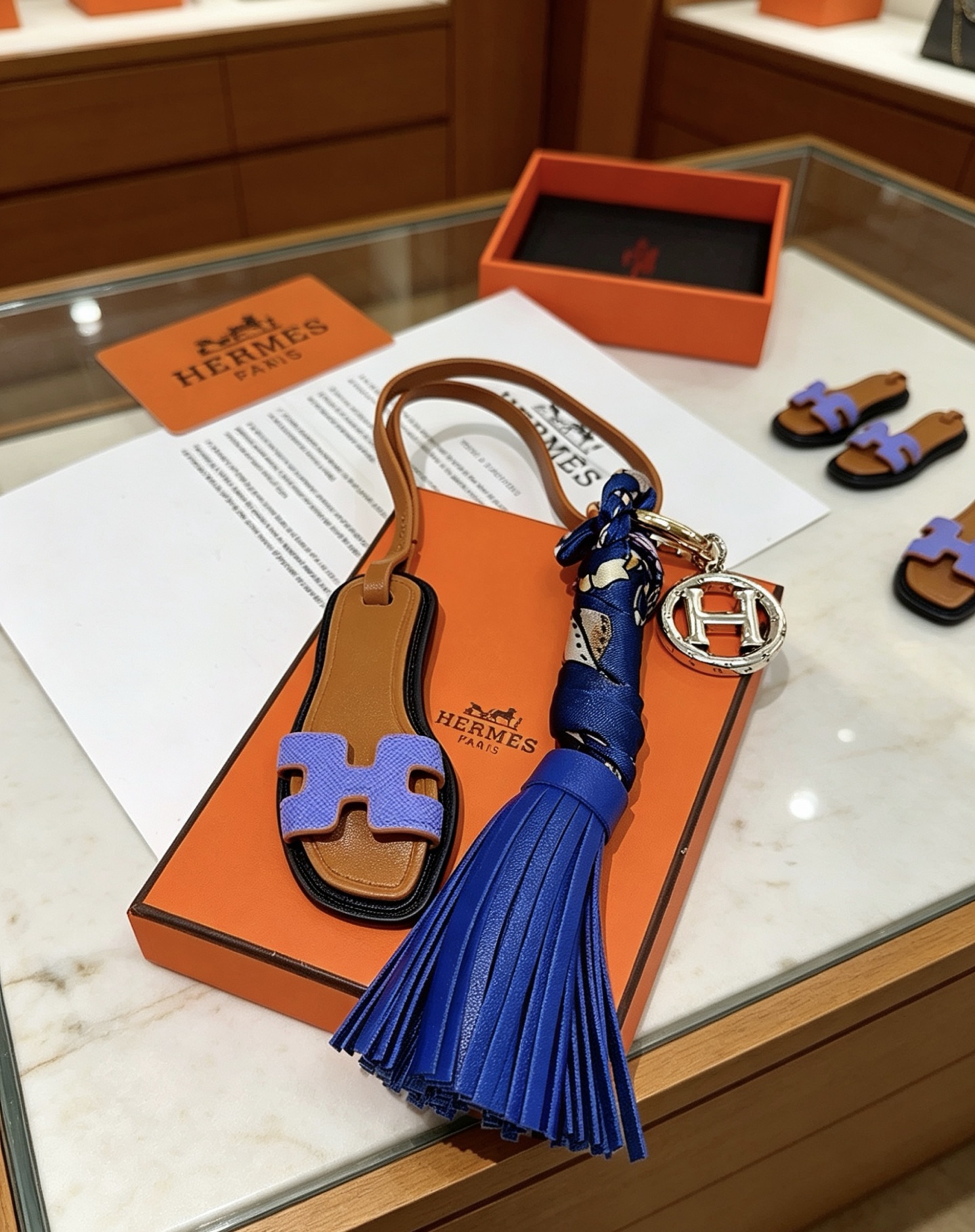 Hermes Oran Sandalo Nappa Chiave Ciondolo con ciondolo Metallo color oro e argento Pelle marrone chiaro Lavanda Pelle viola Pelle blu reale Seta stampata blu scuro Lunghezza totale cinturino 15 cm