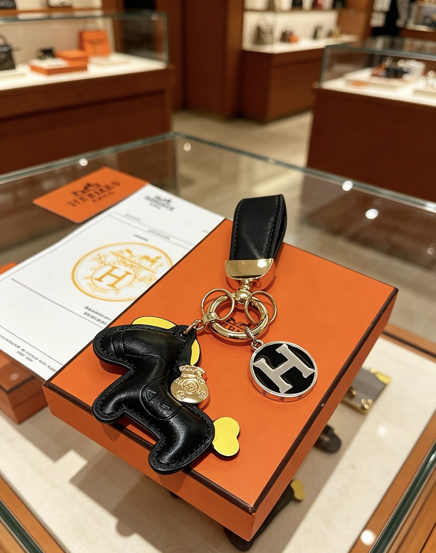Hermes Rodeo Horse H Logo Key Charm colgante Cuero negro acento amarillo metal dorado logo H plateado con esmalte negro 12 cm de longitud total