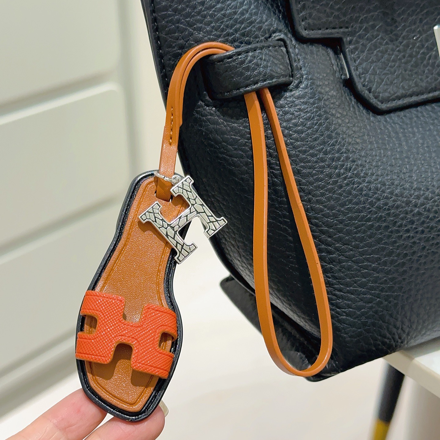 Hermes Oran Sandal Bag Charm colgante Metal plateado naranja Cuero Epsom dorado Cuero Swift ribete de borde negro Longitud de la correa de 17 cm