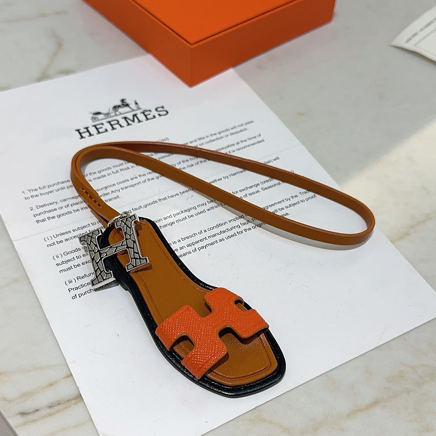 Hermes Oran Sandal Bag Charm colgante Metal plateado naranja Cuero Epsom dorado Cuero Swift ribete de borde negro Longitud de la correa de 17 cm