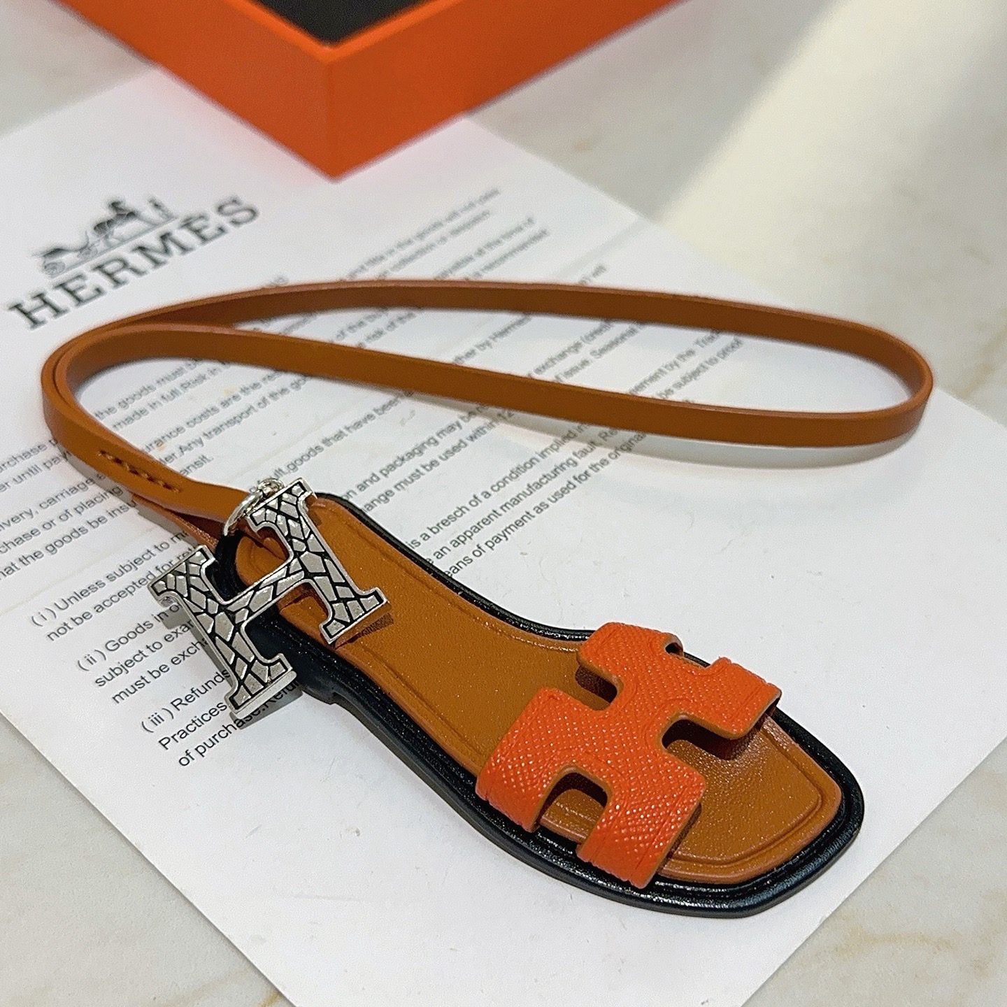 Hermes Oran Sandal Bag Charm colgante Metal plateado naranja Cuero Epsom dorado Cuero Swift ribete de borde negro Longitud de la correa de 17 cm