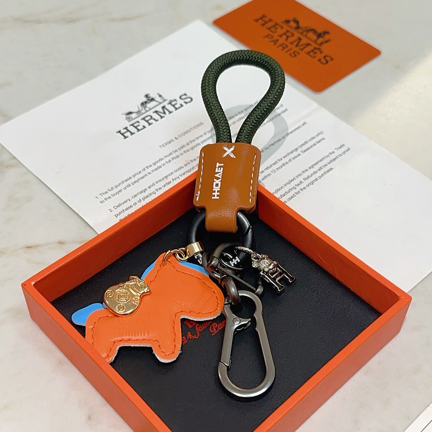 Hermes Rodeo Horse Charm Porte-clés pendentif Breloque cheval en cuir orange avec accents bleus bracelet en cuir marron cordon tressé vert foncé matériel en bronze à canon breloque de sac d'argent doré breloque logo H argenté 10 cm de longueur totale