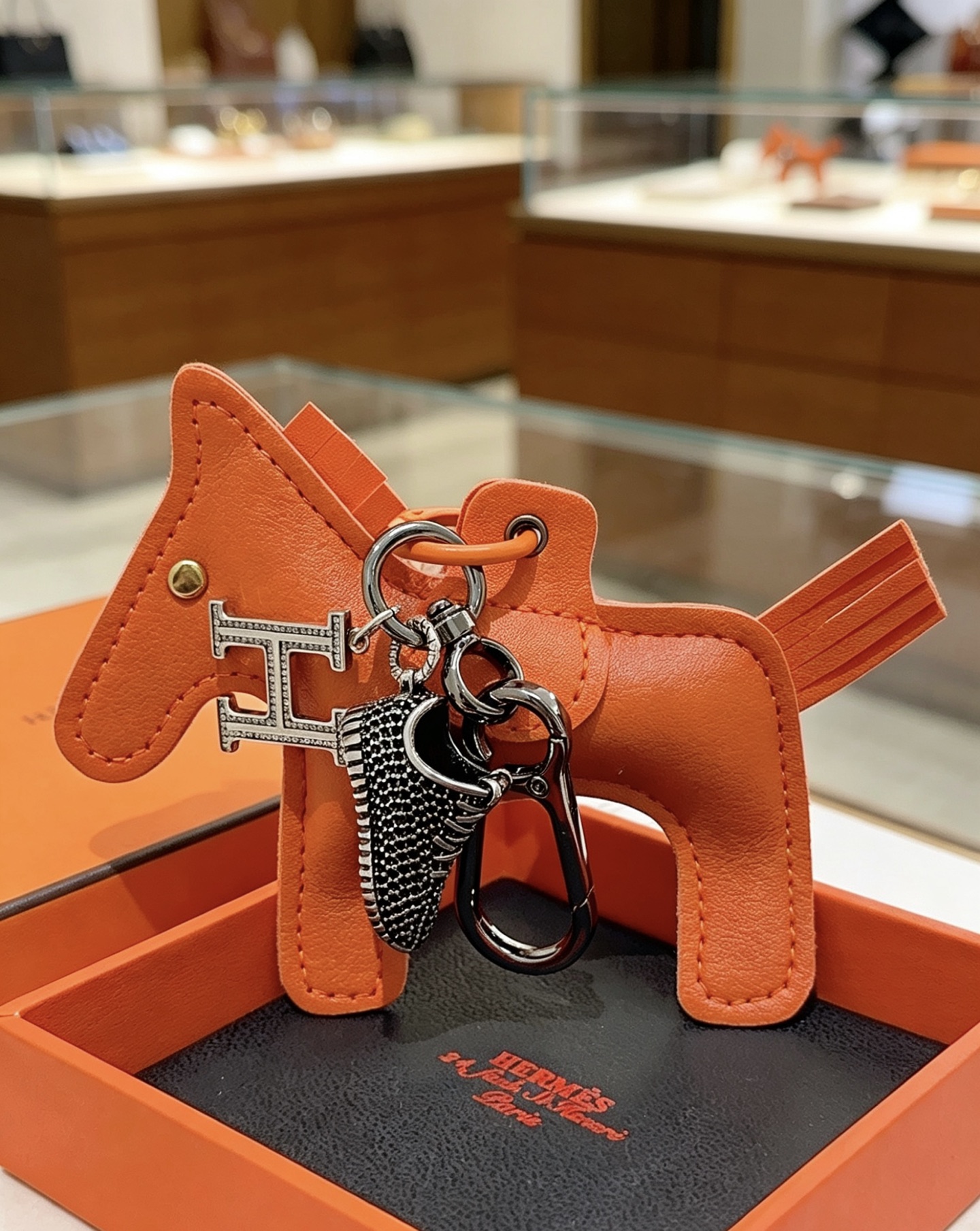 Hermes Rodeo H Logo Sneaker Charm Llavero colgante Herrajes de cuero naranja detalles en cristal transparente Charm de zapatilla en negro y plata 12 cm de longitud total