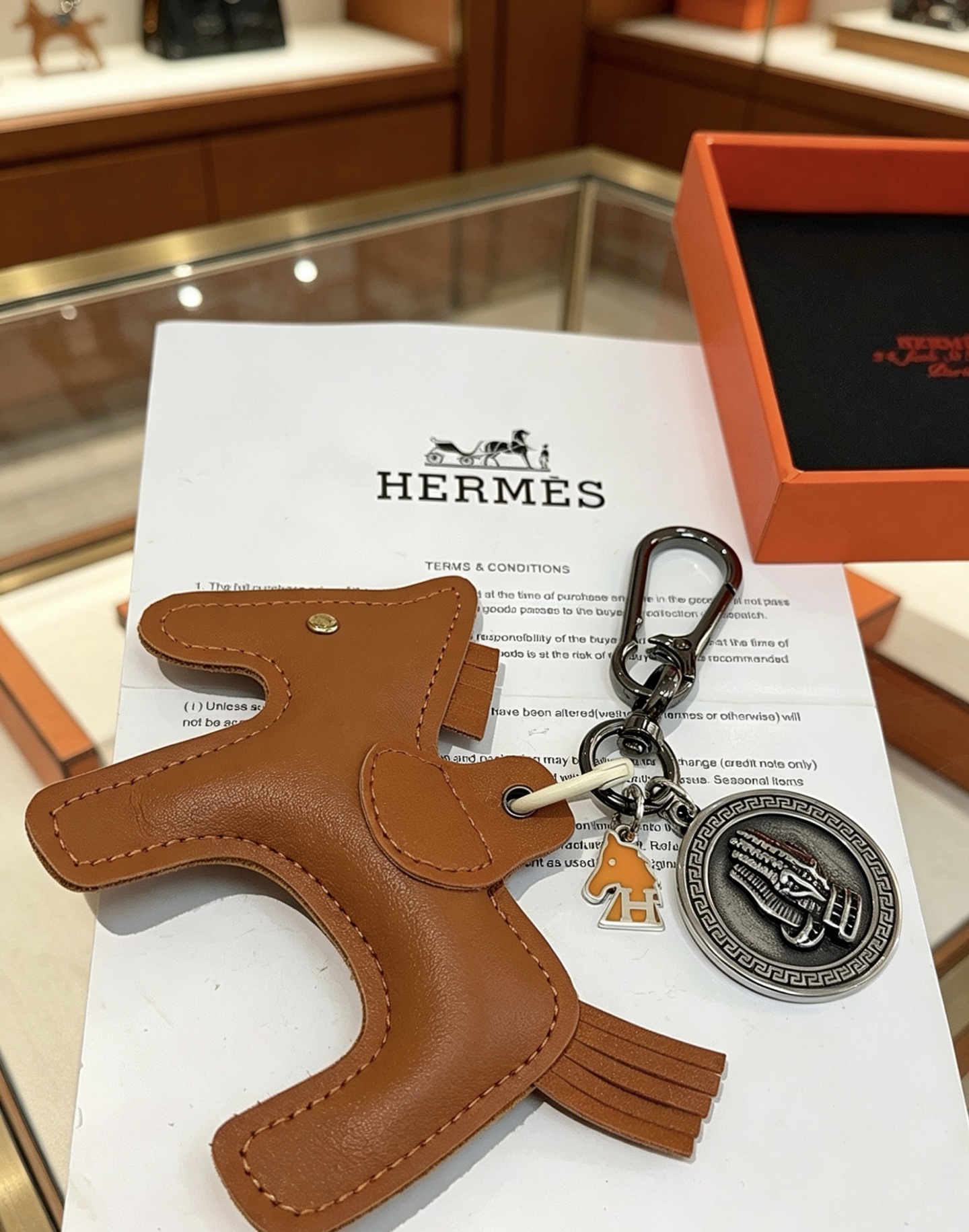 Ciondolo Hermes Cheval con chiave a cavallo, in pelle marrone oro, metallo color argento antico, smalto arancione, lunghezza totale 10 cm
