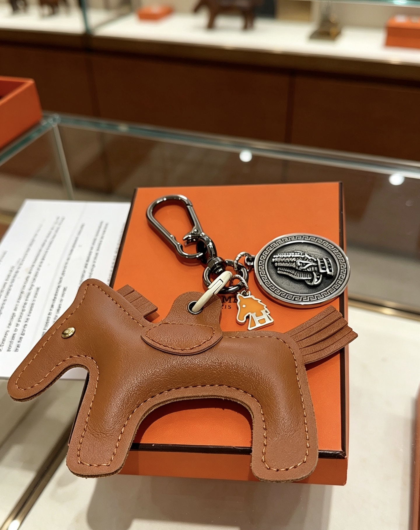Ciondolo Hermes Cheval con chiave a cavallo, in pelle marrone oro, metallo color argento antico, smalto arancione, lunghezza totale 10 cm