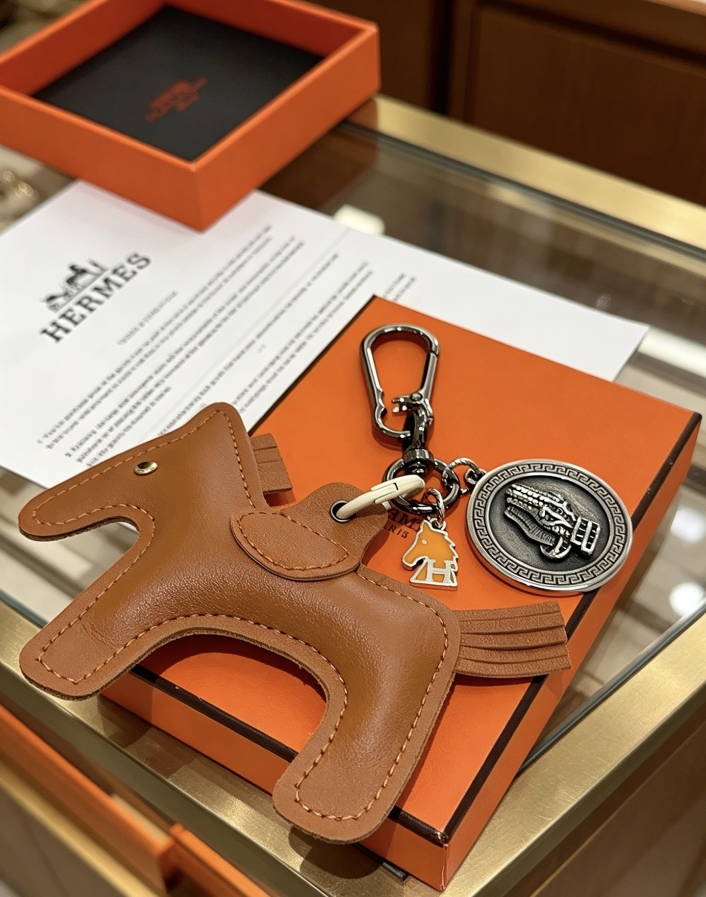 Ciondolo Hermes Cheval con chiave a cavallo, in pelle marrone oro, metallo color argento antico, smalto arancione, lunghezza totale 10 cm