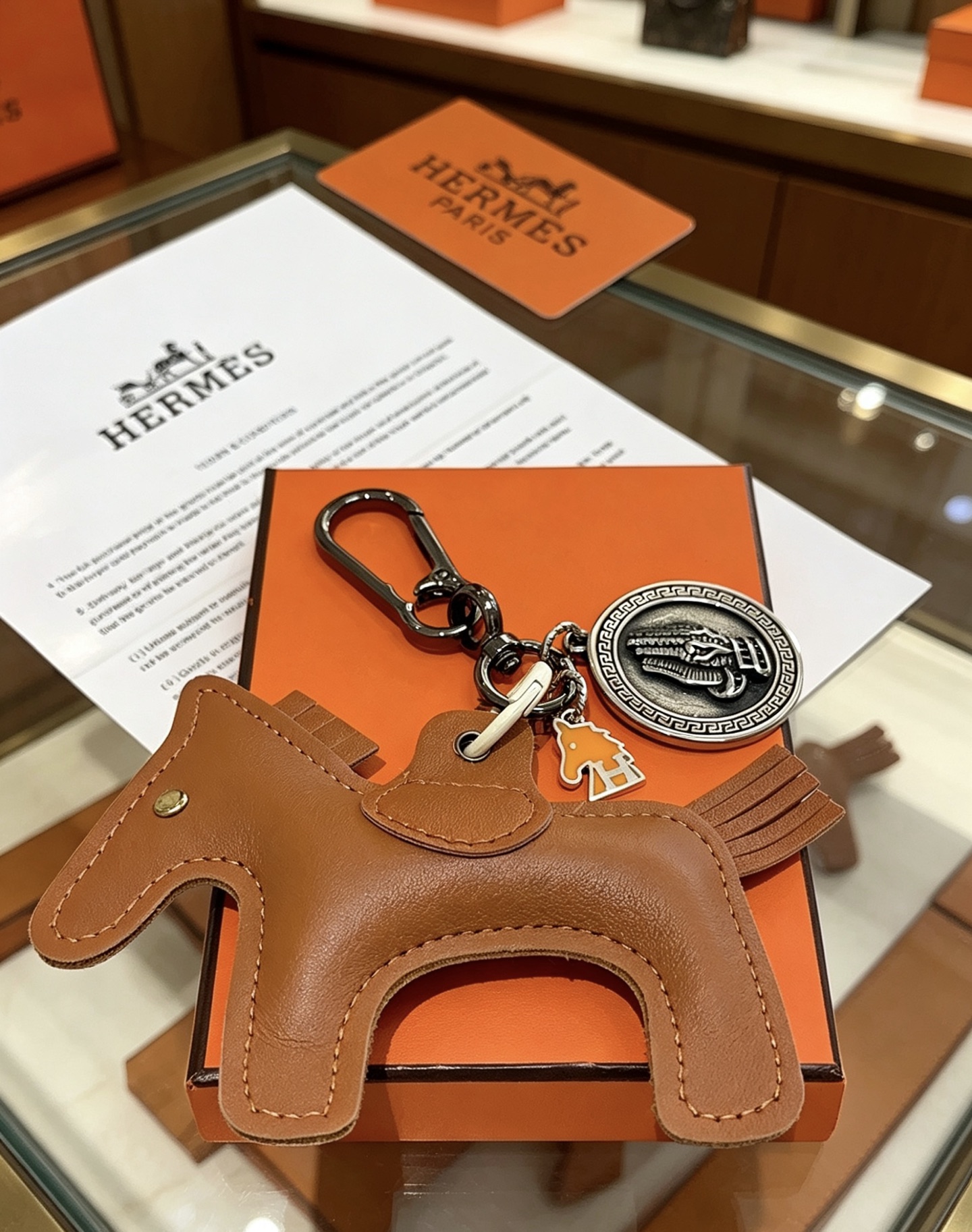 Ciondolo Hermes Cheval con chiave a cavallo, in pelle marrone oro, metallo color argento antico, smalto arancione, lunghezza totale 10 cm