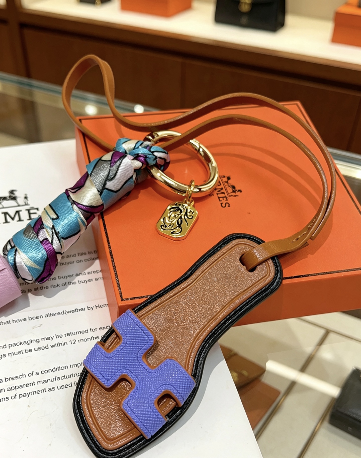 Hermes Oran Sandal Tassel Bag Charm pendant Gold-tone metal tan leather lavender purple leather tassel blue purple white printed silk lilac purple Epsom leather H detail black edge trim 18cm strap length