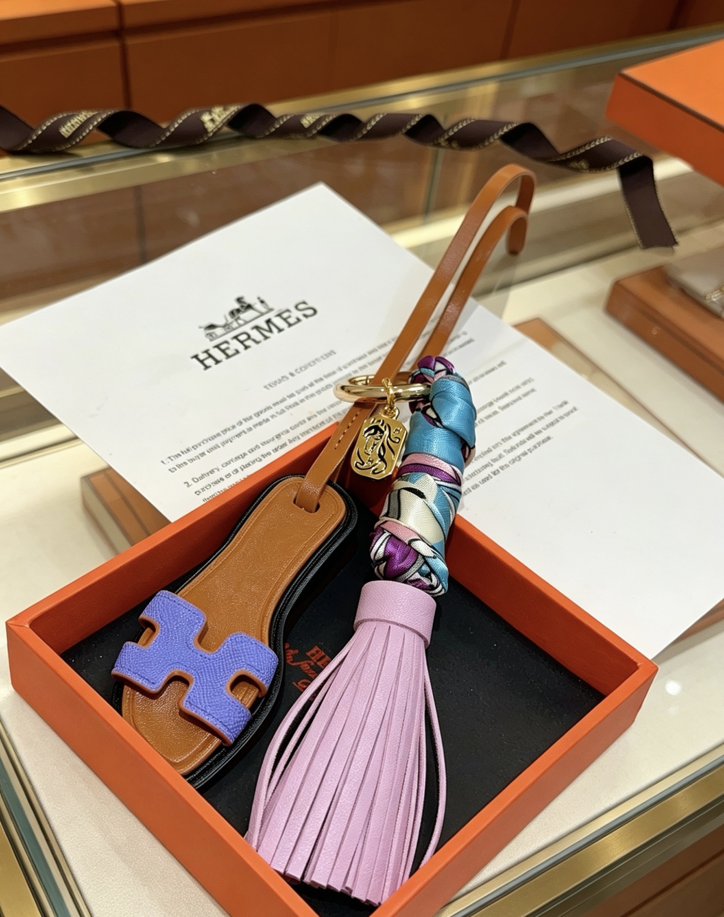 Hermes Oran Sandal Tassel Bag Charm pendant Gold-tone metal tan leather lavender purple leather tassel blue purple white printed silk lilac purple Epsom leather H detail black edge trim 18cm strap length
