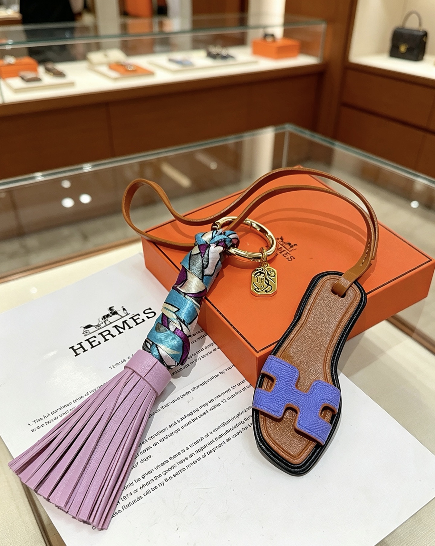 Hermes Oran Sandal Tassel Bag Charm pendant Gold-tone metal tan leather lavender purple leather tassel blue purple white printed silk lilac purple Epsom leather H detail black edge trim 18cm strap length