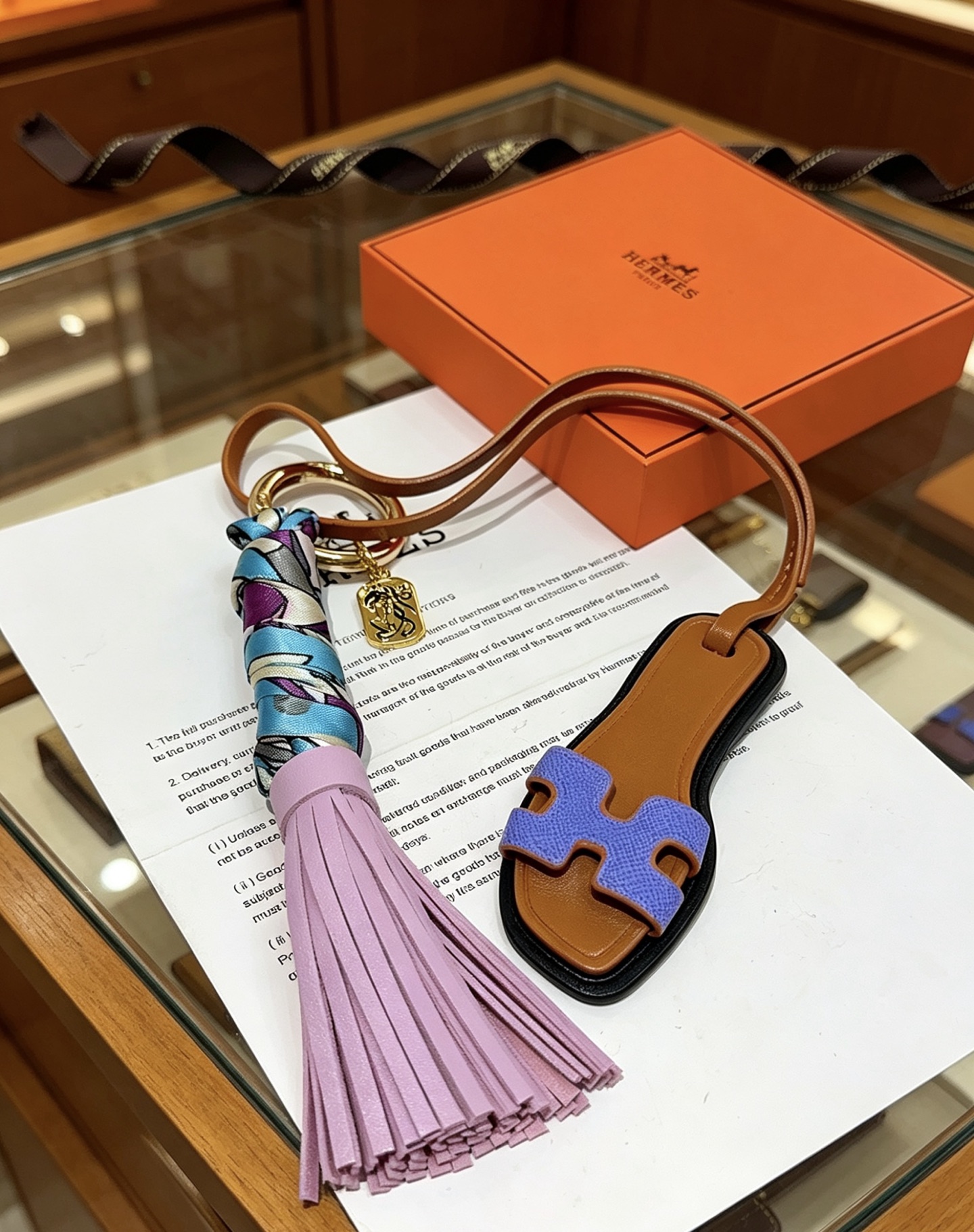 Hermes Oran Sandal Tassel Bag Charm pendant Gold-tone metal tan leather lavender purple leather tassel blue purple white printed silk lilac purple Epsom leather H detail black edge trim 18cm strap length