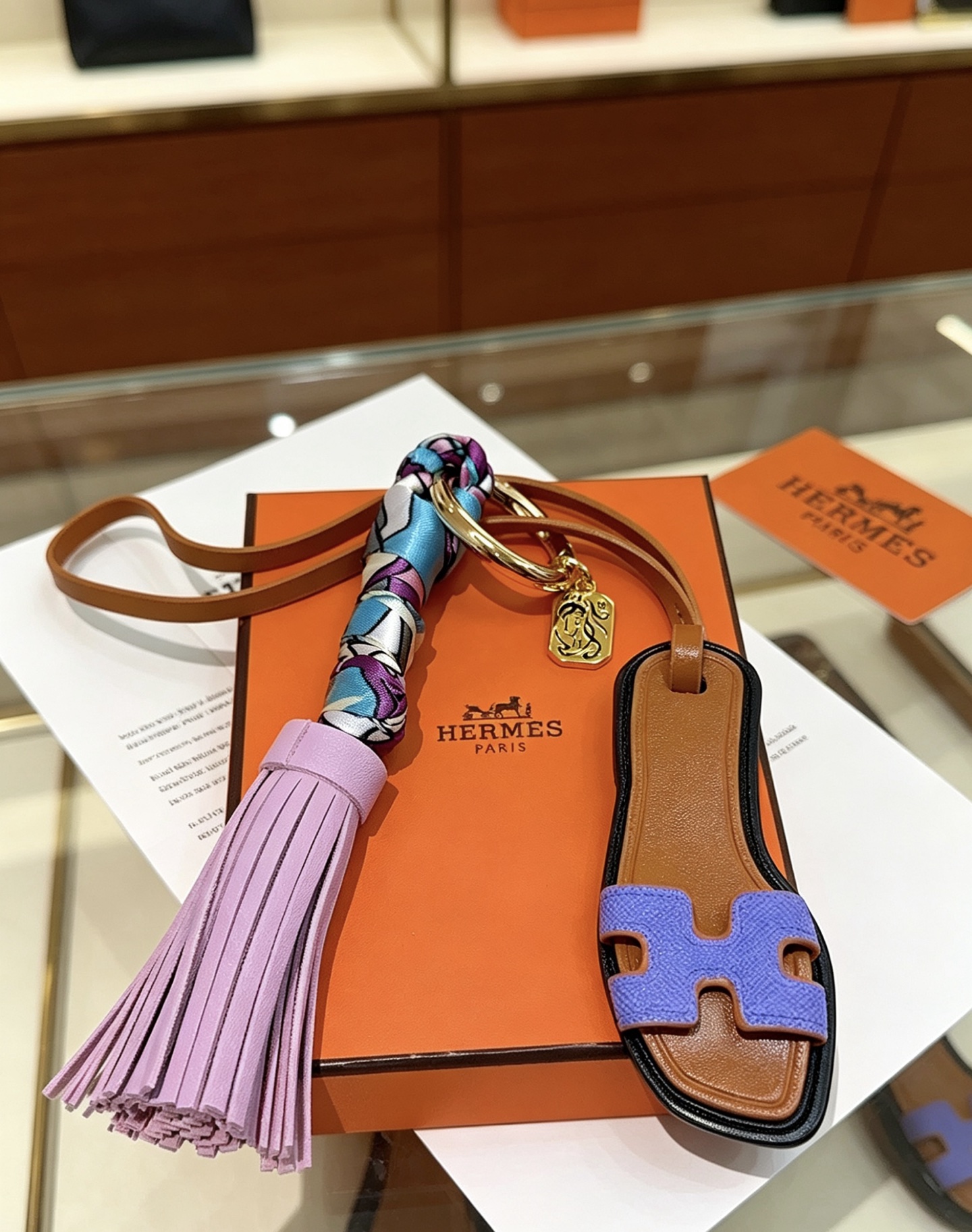 Hermes Oran Sandal Tassel Bag Charm pendant Gold-tone metal tan leather lavender purple leather tassel blue purple white printed silk lilac purple Epsom leather H detail black edge trim 18cm strap length