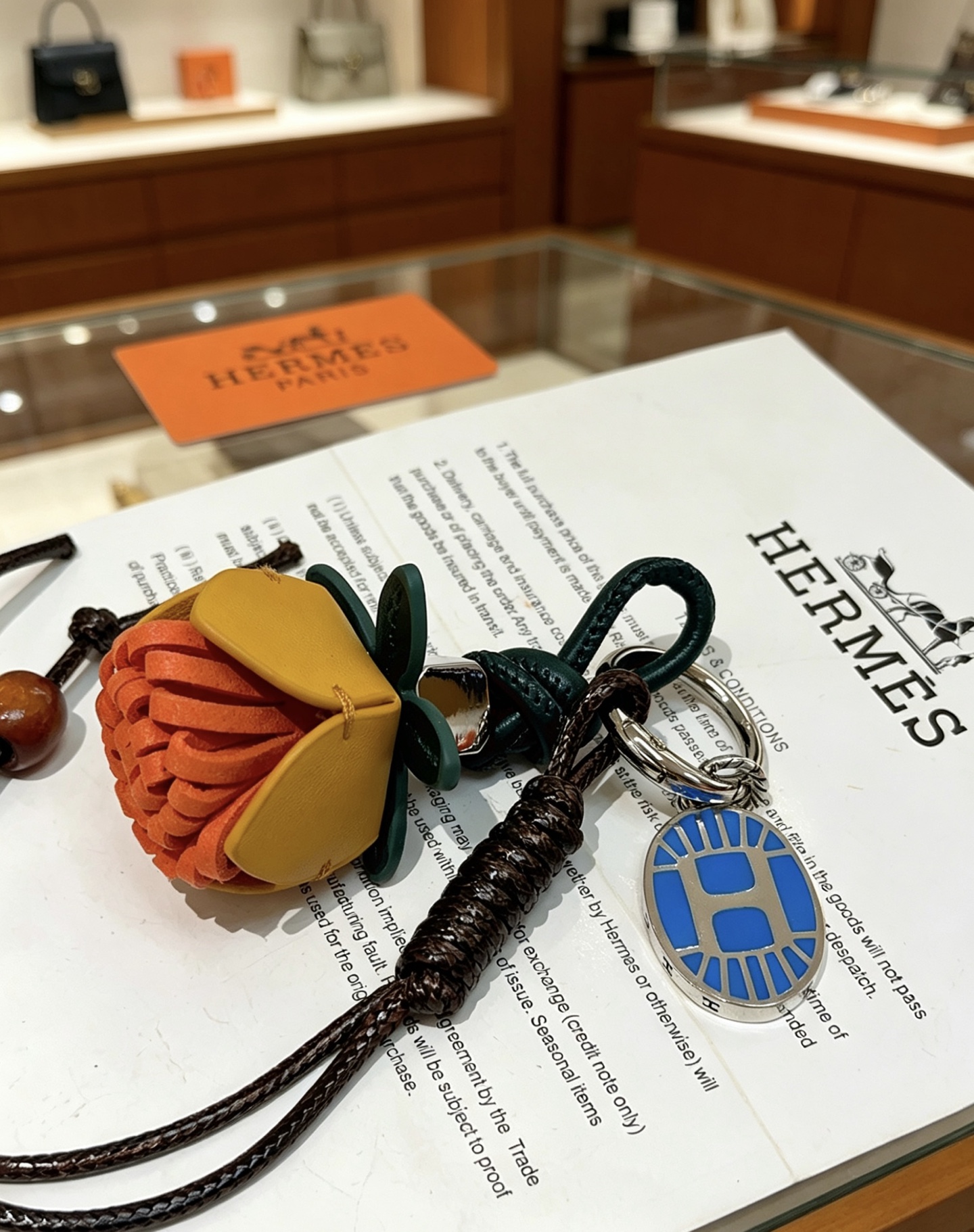 Ciondolo portachiavi con ciondolo a forma di fiore Hermes Protea Metallo color argento con smalto blu pelle multitono arancione giallo senape verde scuro cordone intrecciato nero perline di legno marrone 12 cm di lunghezza totale del cordino