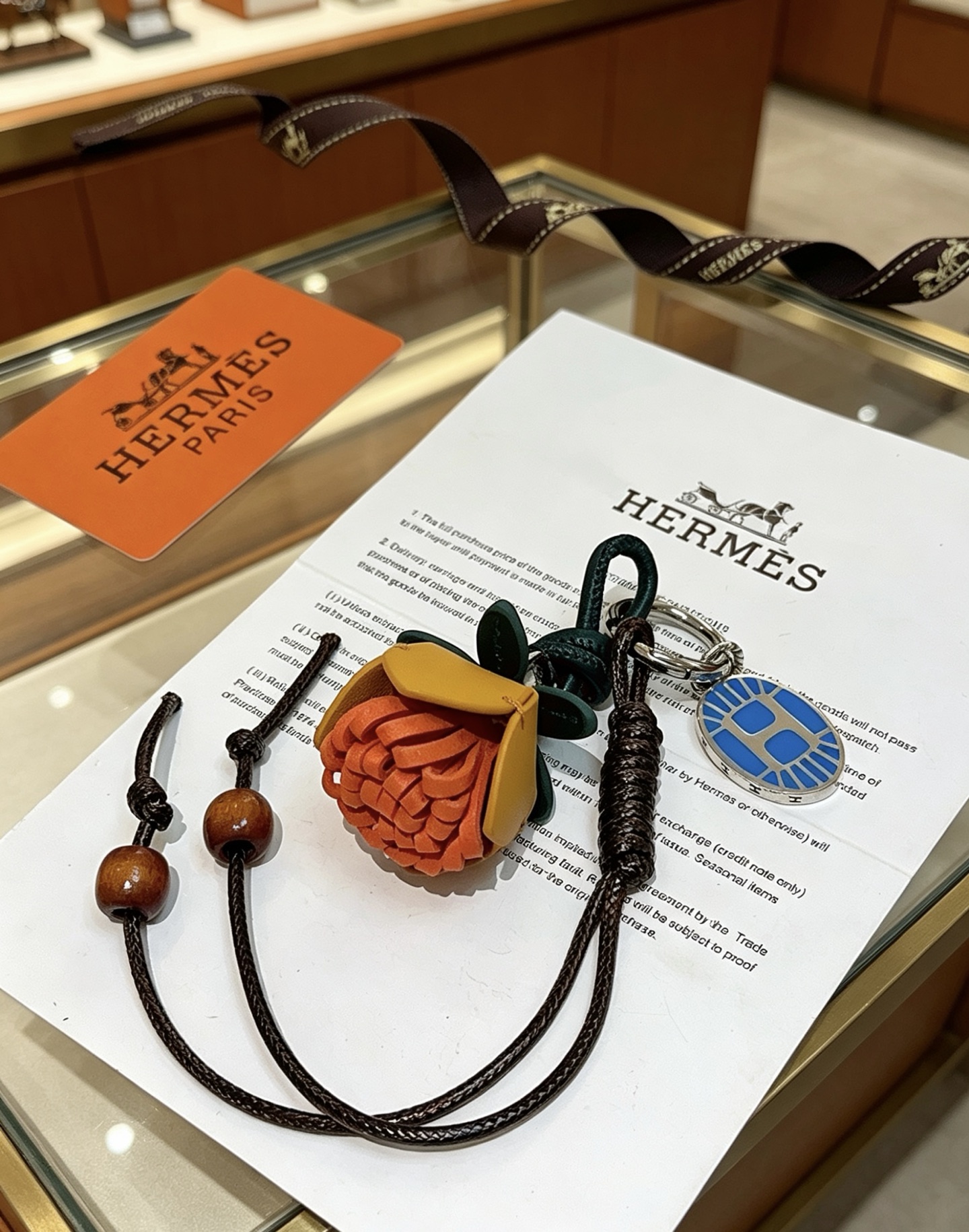 Ciondolo portachiavi con ciondolo a forma di fiore Hermes Protea Metallo color argento con smalto blu pelle multitono arancione giallo senape verde scuro cordone intrecciato nero perline di legno marrone 12 cm di lunghezza totale del cordino