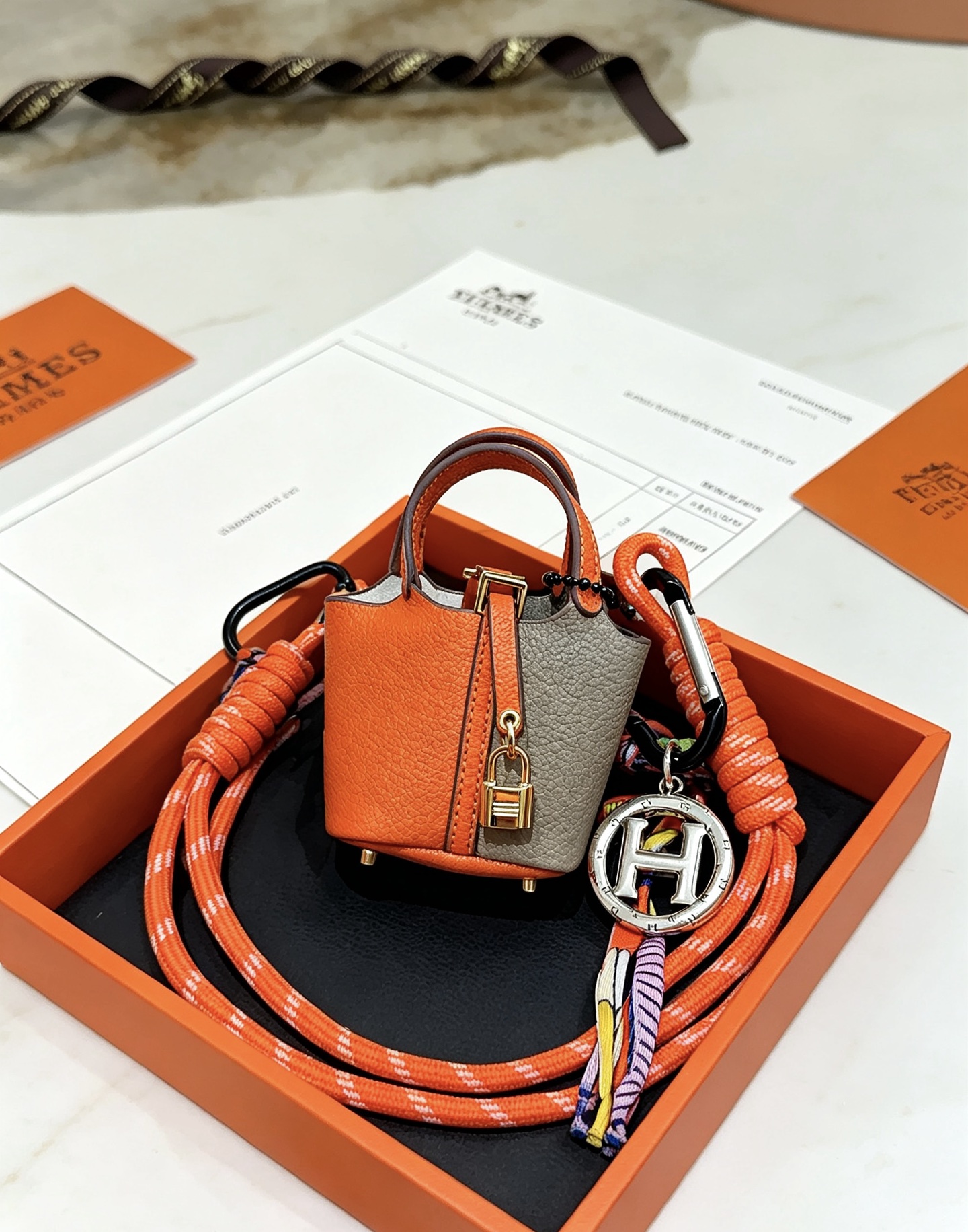 Hermes Mini Picotin Lock Bag Ciondolo con ciondolo Pelle arancione e grigia Hardware in metallo color oro Ciondolo con logo H color argento Accenti di cavo di seta multicolore 80 cm