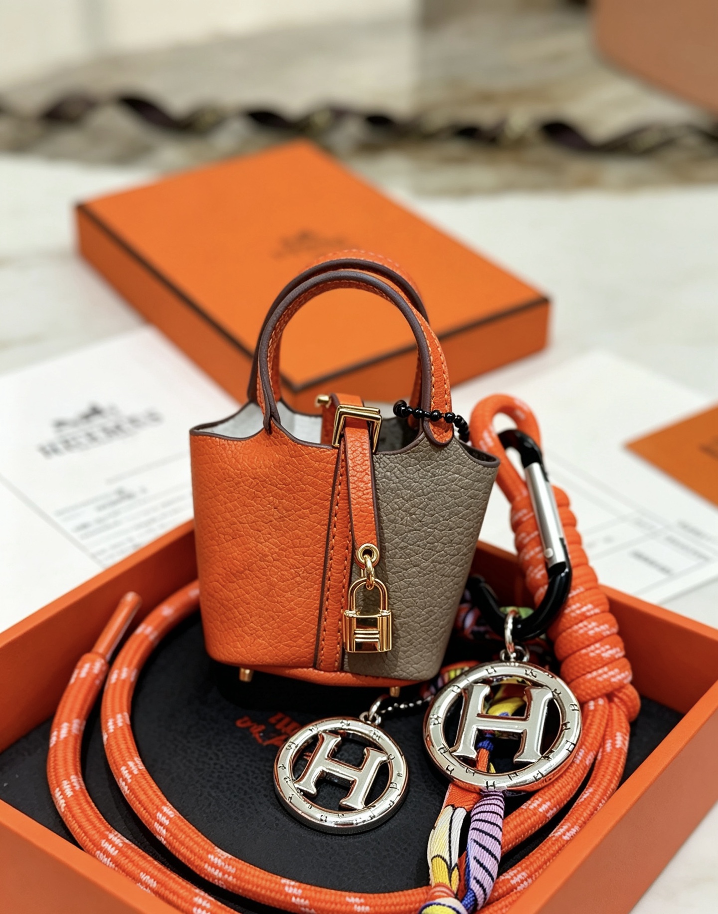 Hermes Mini Picotin Lock Bag Ciondolo con ciondolo Pelle arancione e grigia Hardware in metallo color oro Ciondolo con logo H color argento Accenti di cavo di seta multicolore 80 cm