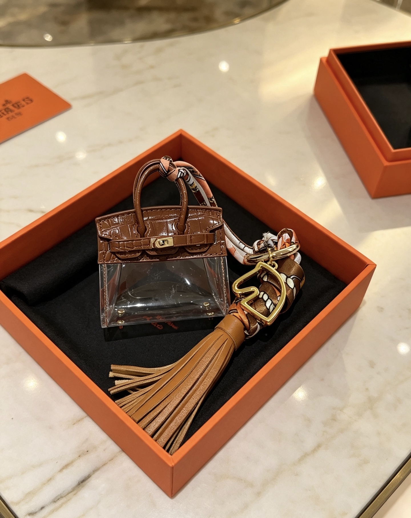 Ciondolo Hermes Birkin Micro Bag Metallo color oro pelle goffrata coccodrillo marrone PVC trasparente nappa in pelle marrone chiaro twilly di seta stampata multicolore lunghezza totale 12 cm
