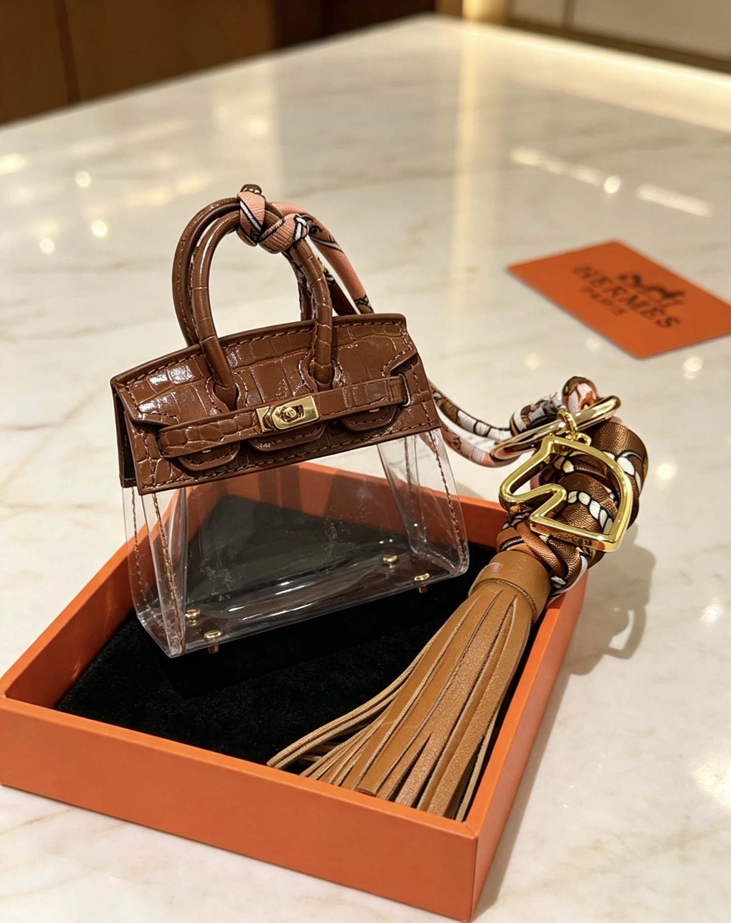 Ciondolo Hermes Birkin Micro Bag Metallo color oro pelle goffrata coccodrillo marrone PVC trasparente nappa in pelle marrone chiaro twilly di seta stampata multicolore lunghezza totale 12 cm