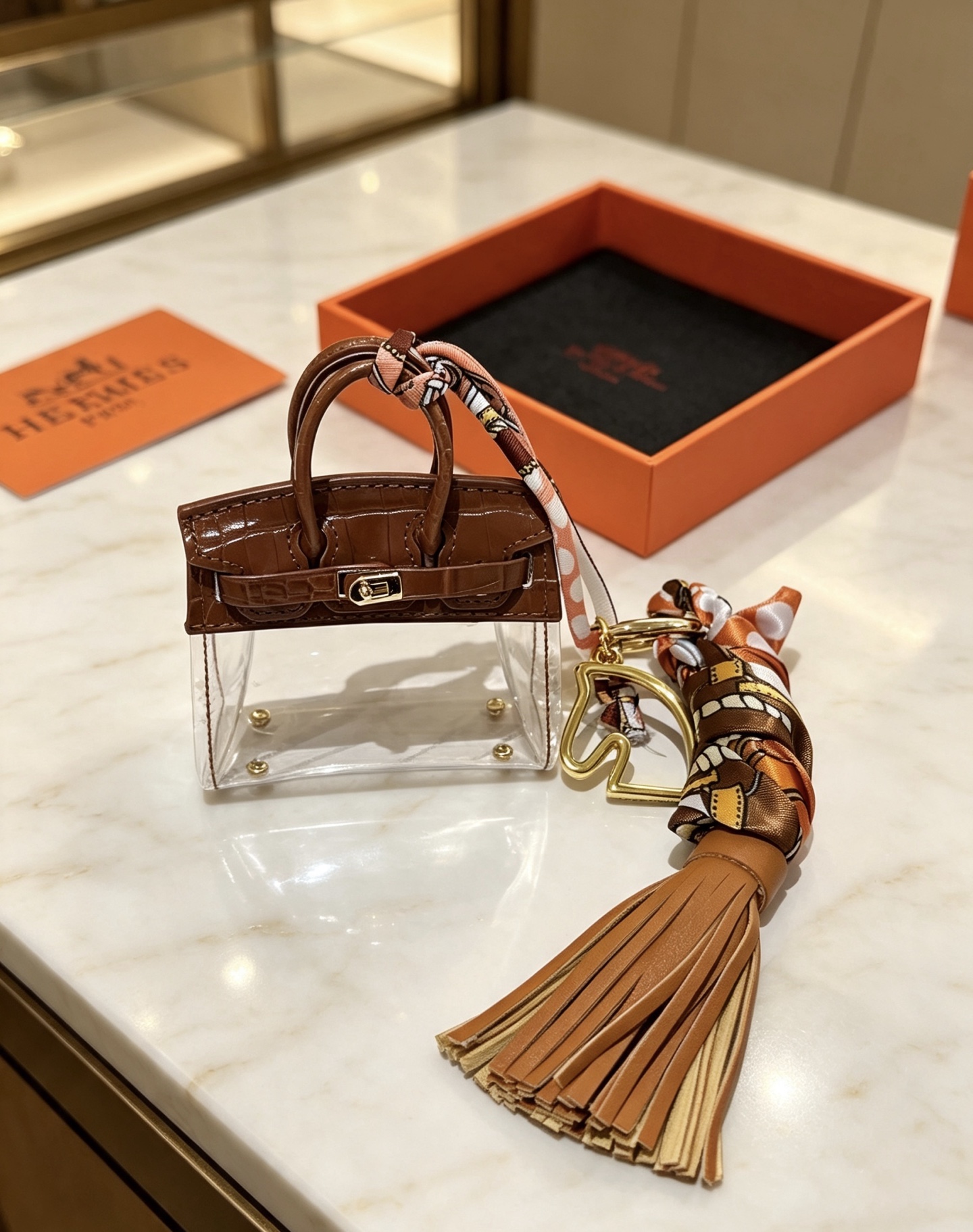 Ciondolo Hermes Birkin Micro Bag Metallo color oro pelle goffrata coccodrillo marrone PVC trasparente nappa in pelle marrone chiaro twilly di seta stampata multicolore lunghezza totale 12 cm