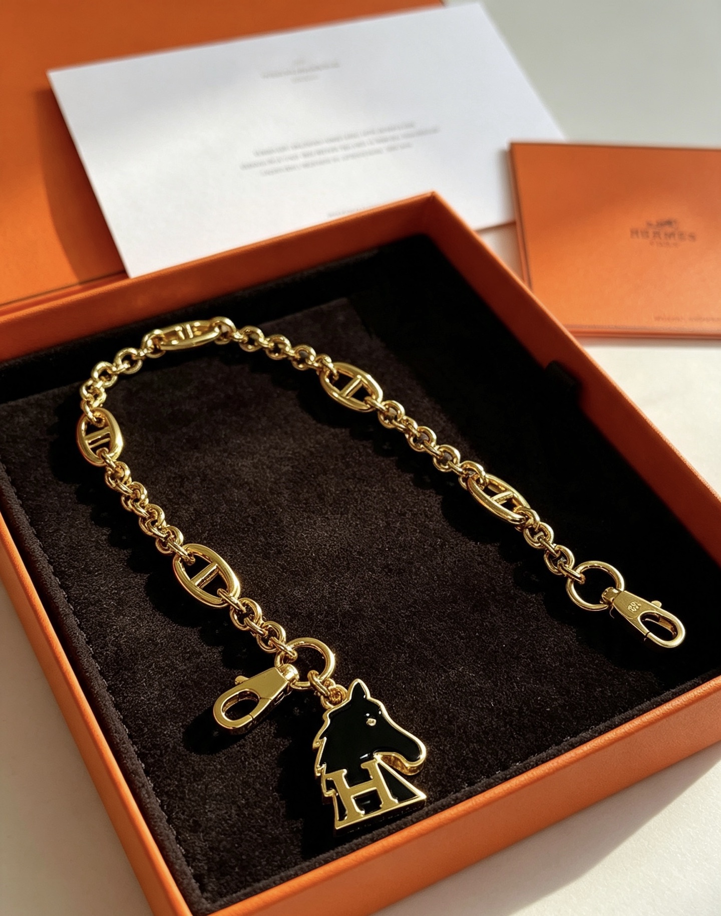 Hermes Cheval H Bag Charm Ciondolo a catena in metallo color oro con smalto nero, lunghezza della catena di 16 cm