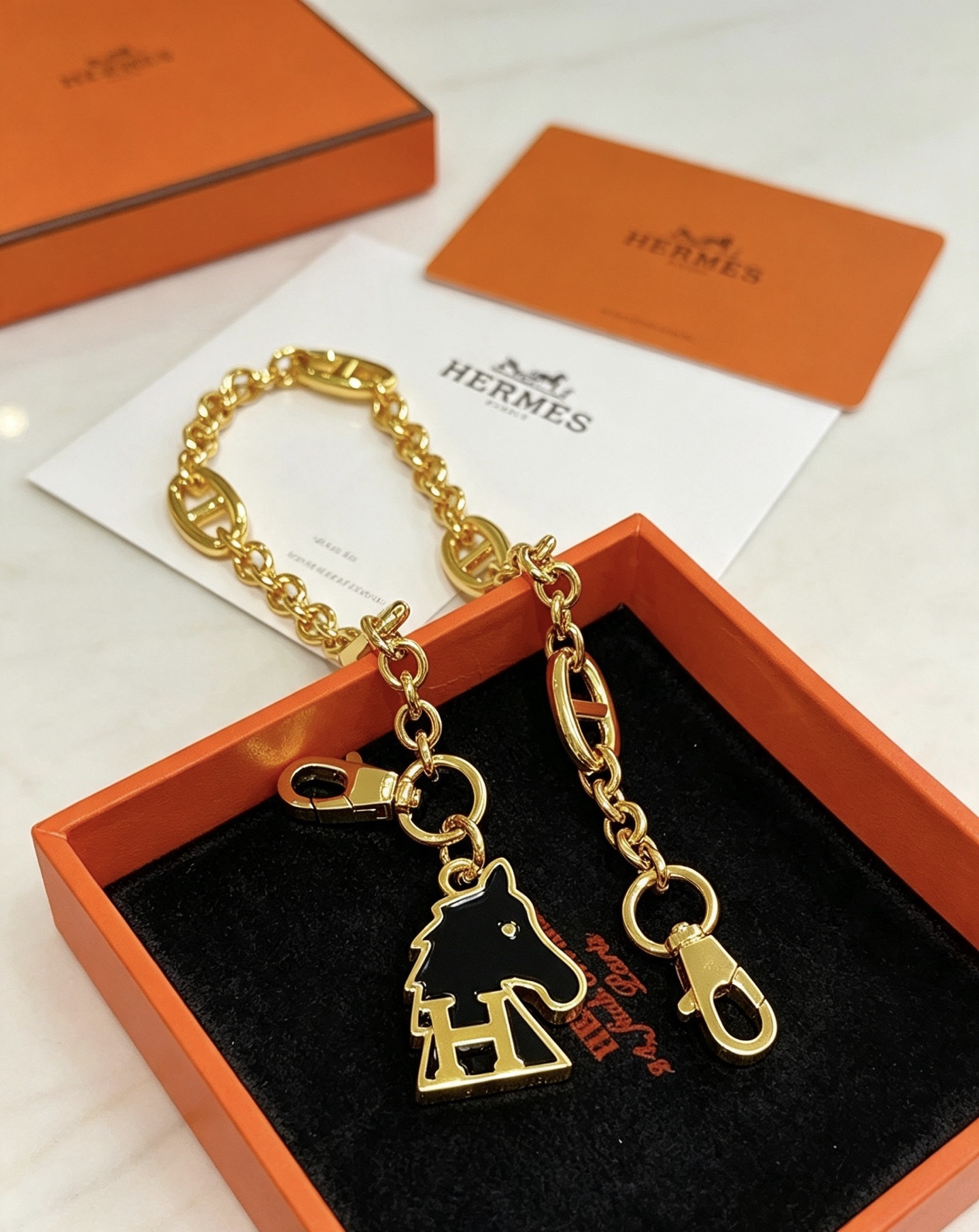 Hermes Cheval H Bag Charm Ciondolo a catena in metallo color oro con smalto nero, lunghezza della catena di 16 cm