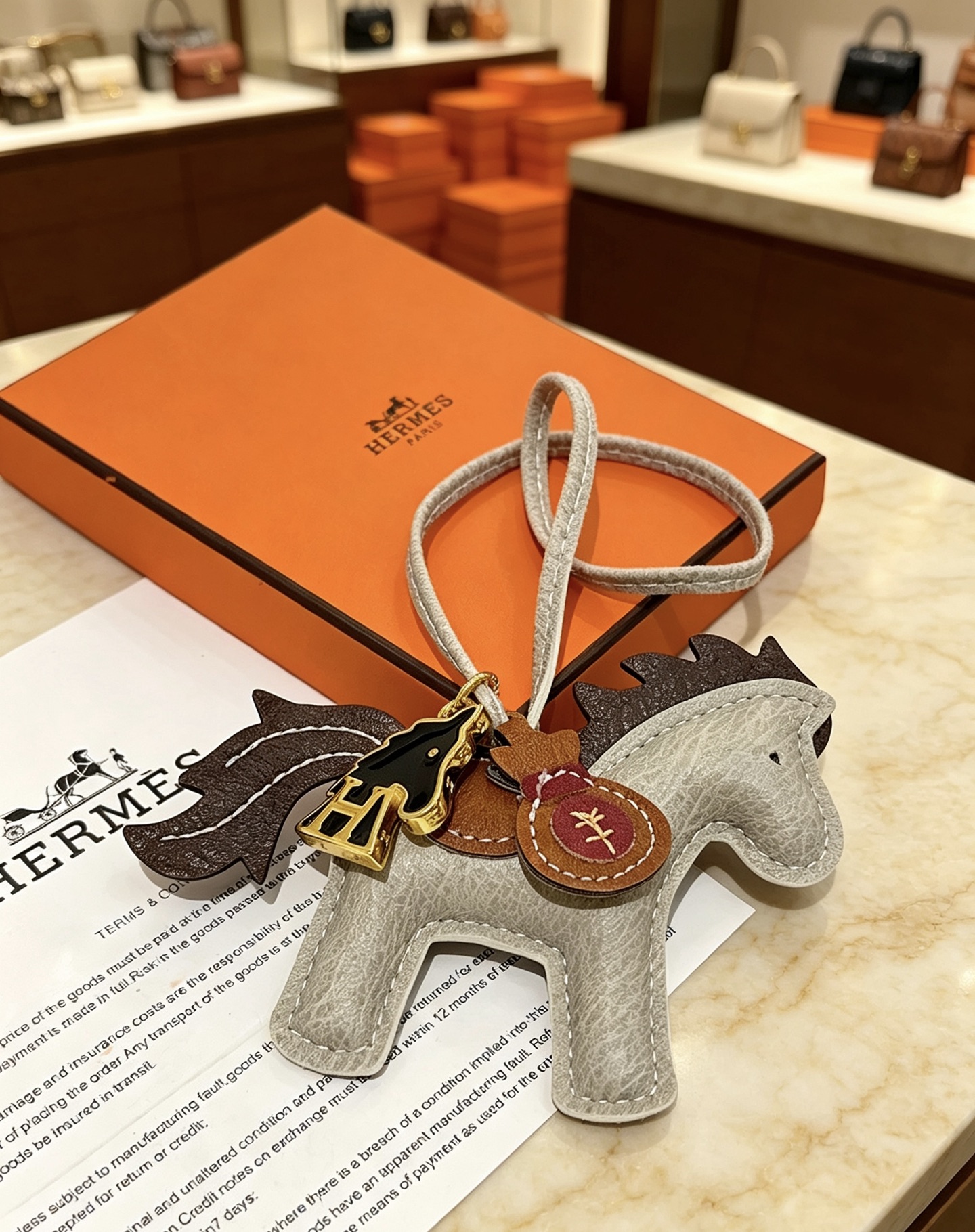 Ciondolo Hermes Rodeo Pegase Horse Bag Charm in pelle grigio chiaro con coda di criniera in pelle marrone scuro, sella in pelle marrone chiaro, hardware in metallo color oro, smalto nero, H cavallo, ciondolo per borsa di denaro in pelle bordeaux, ciondolo da 8 cm con cinturino in pelle da 12 cm.