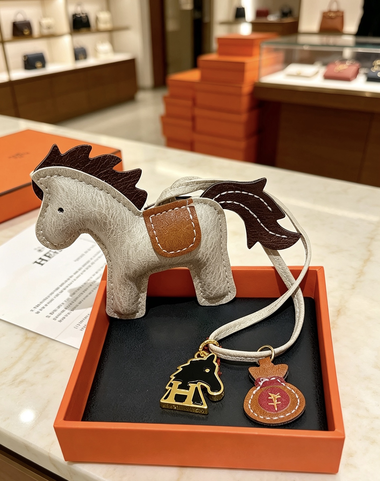 Ciondolo Hermes Rodeo Pegase Horse Bag Charm in pelle grigio chiaro con coda di criniera in pelle marrone scuro, sella in pelle marrone chiaro, hardware in metallo color oro, smalto nero, H cavallo, ciondolo per borsa di denaro in pelle bordeaux, ciondolo da 8 cm con cinturino in pelle da 12 cm.