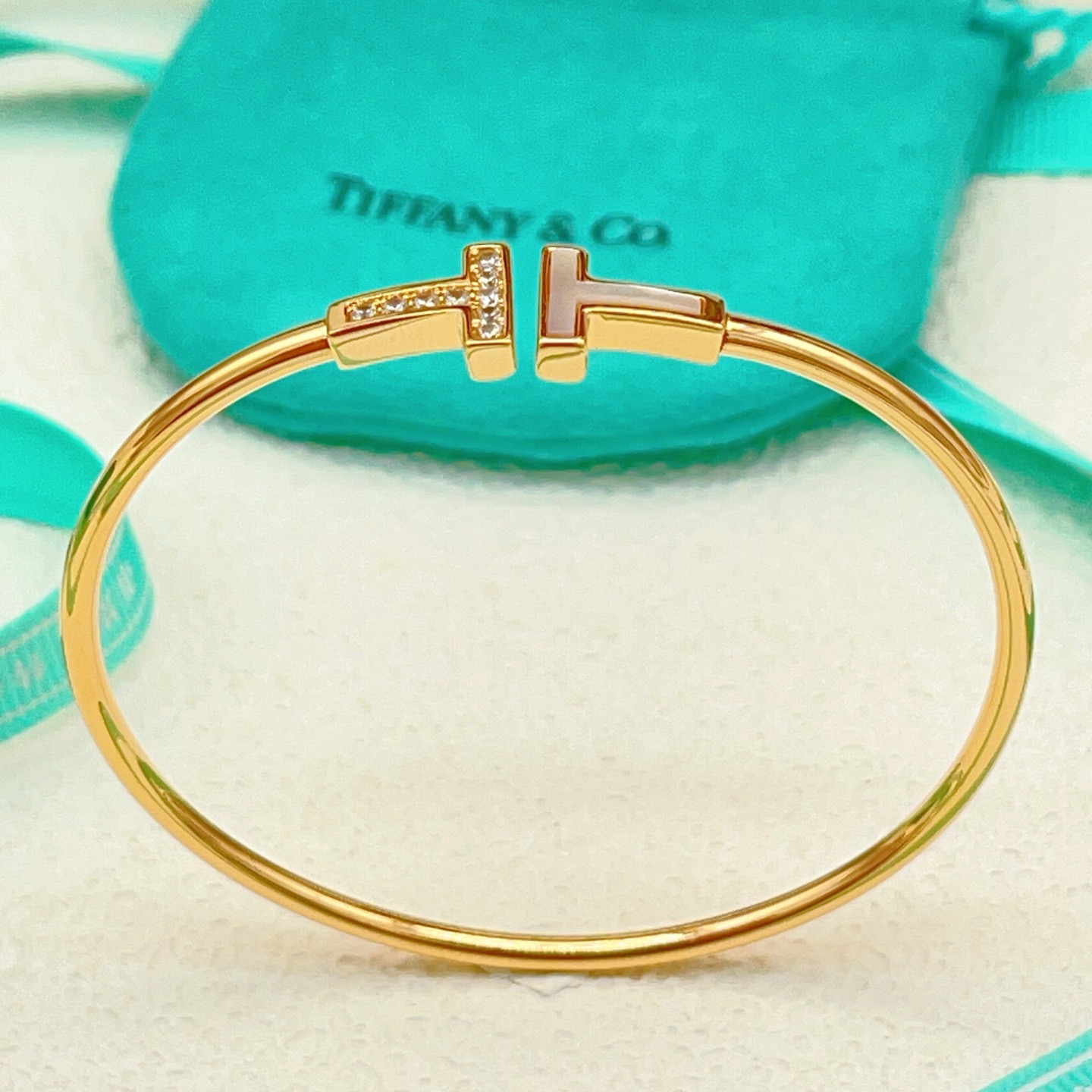 Tiffany Co T Wire bracelet yellow gold metal with white mother-of-pearl and clear diamond accents 17cm inner circumference