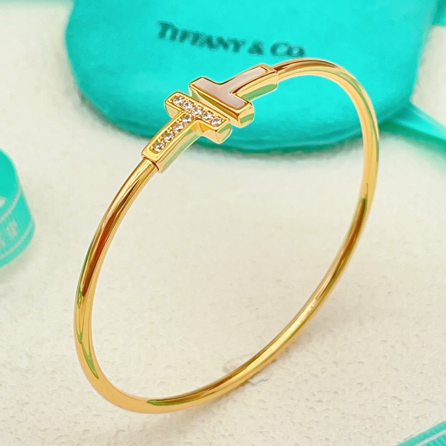 Tiffany Co T Wire bracelet yellow gold metal with white mother-of-pearl and clear diamond accents 17cm inner circumference
